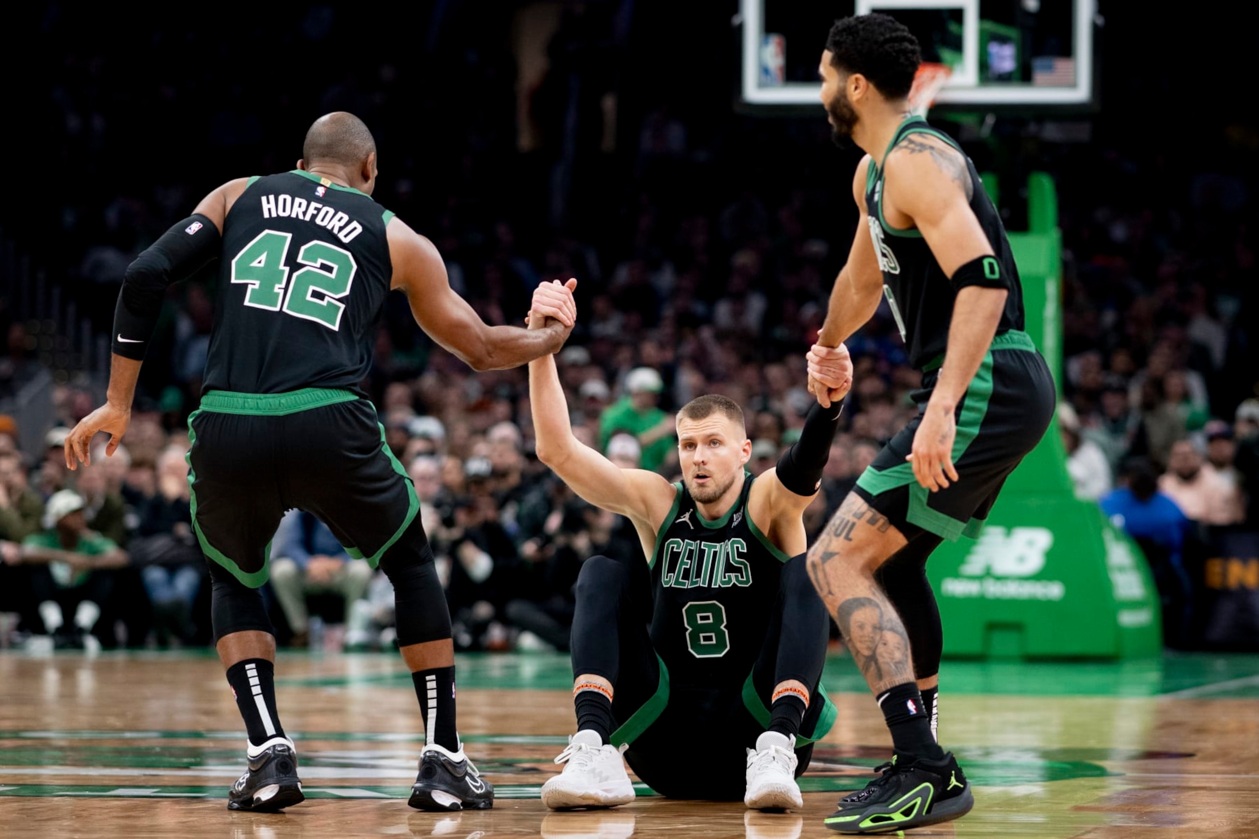 BOSTON, MASSACHUSETTS - NOVEMBER 13: Al Horford #42 of the Boston Celtics and Jayson Tatum #0 of the Boston Celtics help Kristaps Porzingis #8 of the Boston Celtics off the ground against the New York Knicks at TD Garden on November 13, 2023 in Boston, Massachusetts. NOTE TO USER: User expressly acknowledges and agrees that, by downloading and or using this photograph, User is consenting to the terms and conditions of the Getty Images License Agreement. (Photo by Maddie Malhotra/Getty Images)