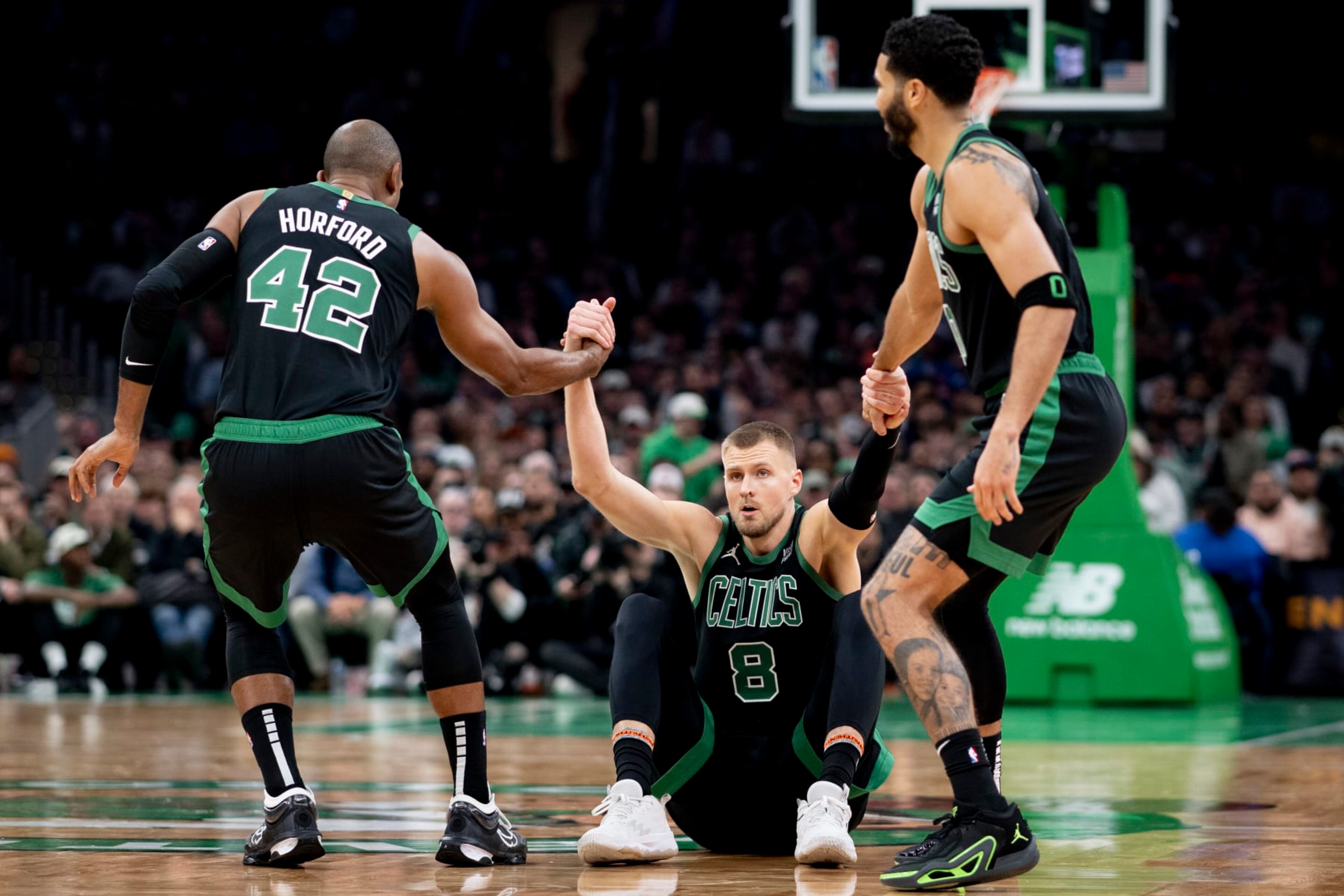 BOSTON, MASSACHUSETTS - NOVEMBER 13: Al Horford #42 of the Boston Celtics and Jayson Tatum #0 of the Boston Celtics help Kristaps Porzingis #8 of the Boston Celtics off the ground against the New York Knicks at TD Garden on November 13, 2023 in Boston, Massachusetts. NOTE TO USER: User expressly acknowledges and agrees that, by downloading and or using this photograph, User is consenting to the terms and conditions of the Getty Images License Agreement. (Photo by Maddie Malhotra/Getty Images)