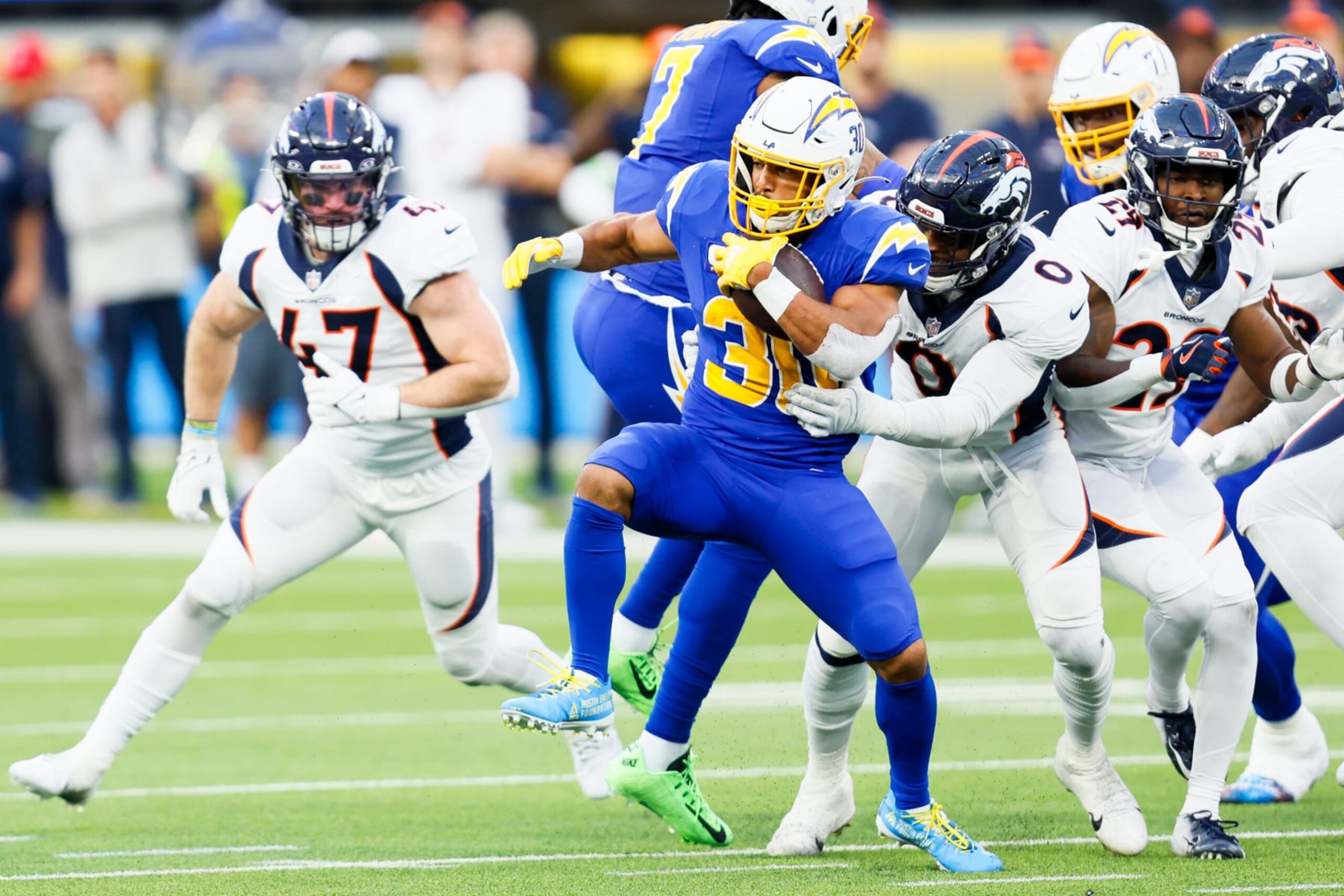 Inglewood, CA - December 10: Los Angeles Chargers running back Austin Ekeler (30) runs the ball while Denver Broncos linebacker Jonathon Cooper (0) attempts a tackle during the second half at SoFi Stadium in Inglewood Sunday, Dec. 10, 2023.  (Allen J. Schaben / Los Angeles Times via Getty Images)