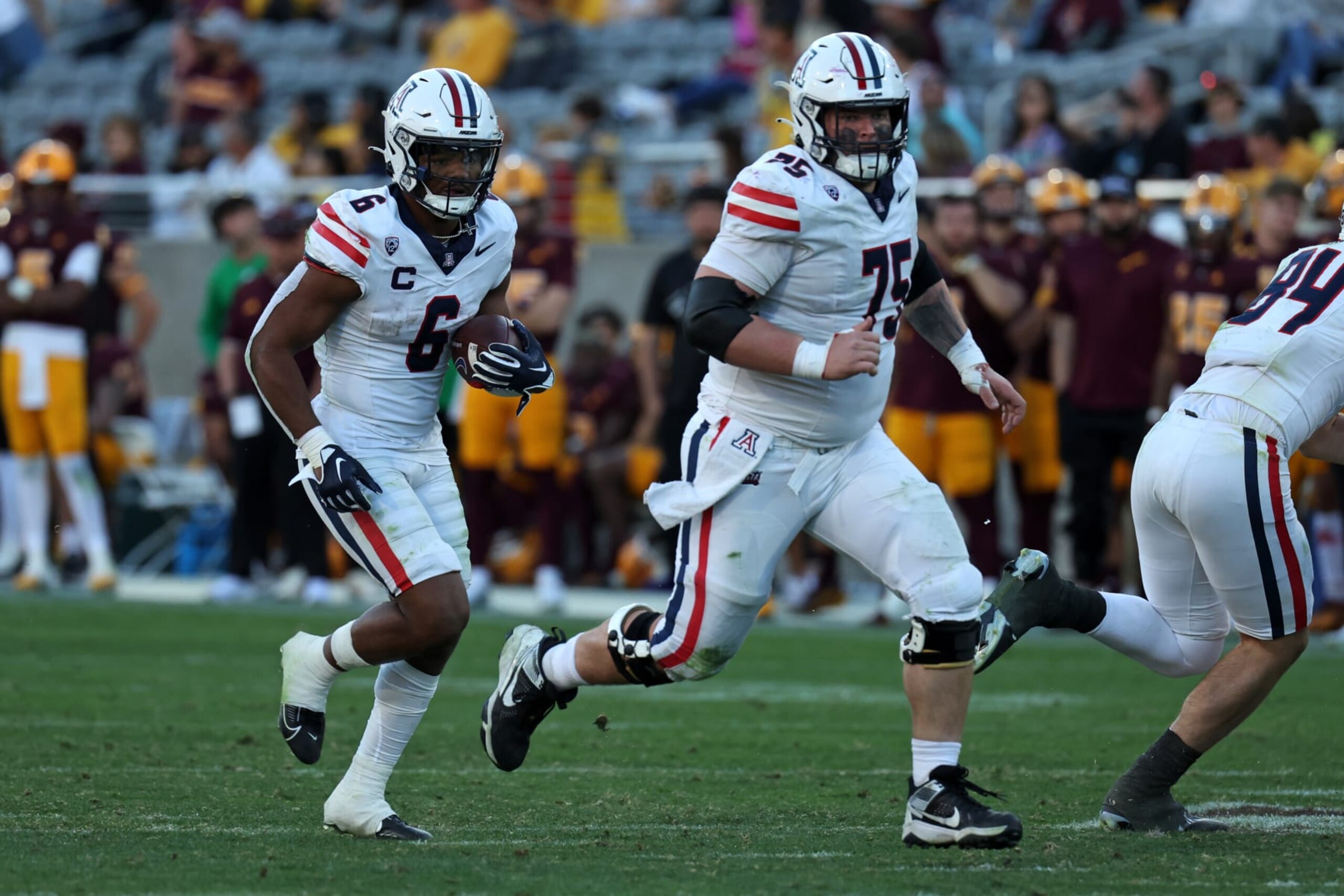 TEMPE, AZ - NOVEMBER 25: Arizona Wildcats running back Michael Wiley (6) runs the ball with Arizona Wildcats offensive lineman Josh Baker (75) during the second half of a football game between the Arizona Wildcats and the Arizona State Sun Devils on November 25, 2023, at Mullett Arena in Tempe, AZ. (Photo by Zac BonDurant/Icon Sportswire via Getty Images) TEMPE, AZ - NOVEMBER 25: Arizona Wildcats running back Michael Wiley (6) runs the ball with Arizona Wildcats offensive lineman Josh Baker (75) during the second half of a football game between the Arizona Wildcats and the Arizona State Sun Devils on November 25, 2023, at Mullett Arena in Tempe, AZ. (Photo by Zac BonDurant/Icon Sportswire via Getty Images)