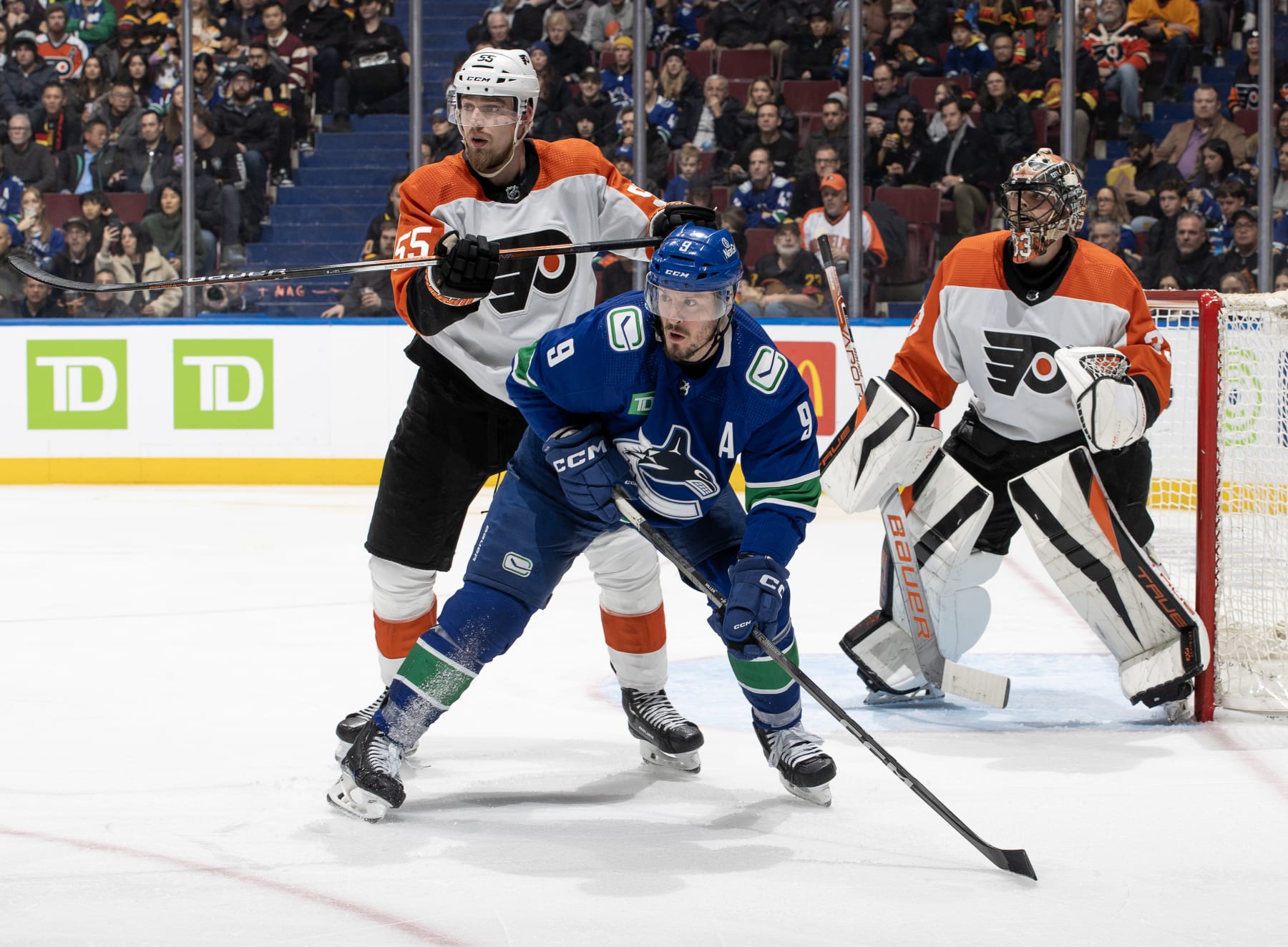 VANCOUVER, CANADA - DECEMBER 28: J.T. Miller #9 of the Vancouver Canucks and Rasmus Ristolainen #55 of the Philadelphia Flyers battle for the puck during the second period of their NHL game at Rogers Arena on December 28, 2023 in Vancouver, British Columbia, Canada.  (Photo by Jeff Vinnick/NHLI via Getty Images)