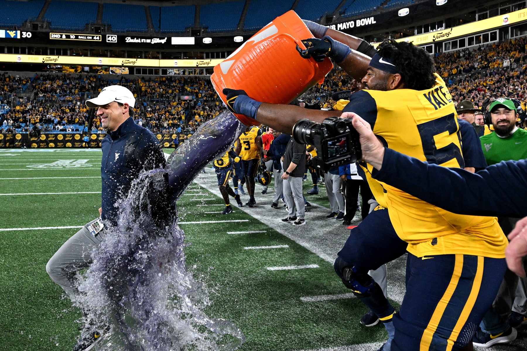 CHARLOTTE, NORTH CAROLINA - DECEMBER 27: Brandon Yates #50 dunks head coach Neal Brown of the West Virginia Mountaineers to celebraate after a win against the North Carolina Tar Heels in the Duke's Mayo Bowl at Bank of America Stadium on December 27, 2023 in Charlotte, North Carolina. West Virginia won 30-10. (Photo by Grant Halverson/Getty Images)