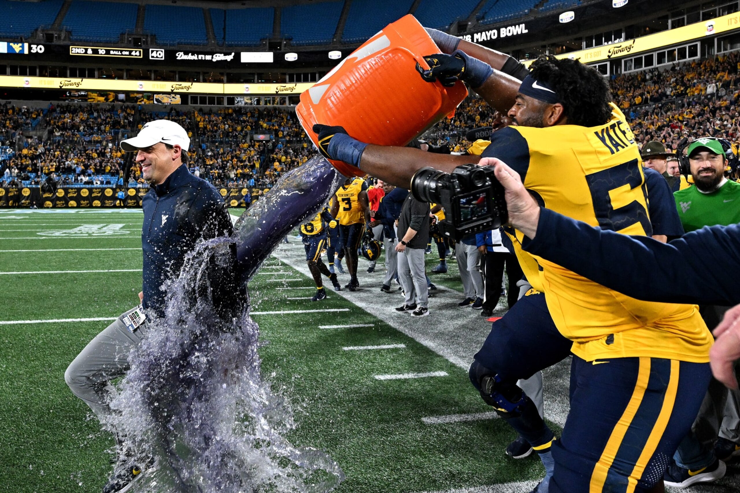 CHARLOTTE, NORTH CAROLINA - DECEMBER 27: Brandon Yates #50 dunks head coach Neal Brown of the West Virginia Mountaineers to celebraate after a win against the North Carolina Tar Heels in the Duke's Mayo Bowl at Bank of America Stadium on December 27, 2023 in Charlotte, North Carolina. West Virginia won 30-10. (Photo by Grant Halverson/Getty Images)