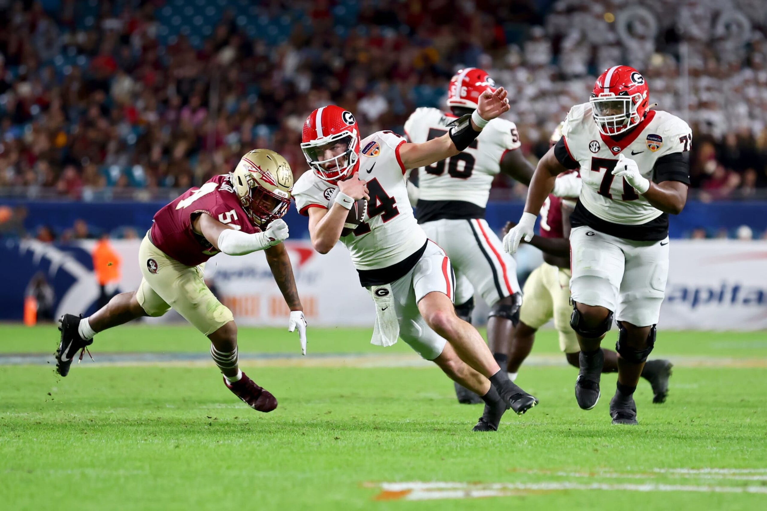 MIAMI GARDENS, FLORIDA - DECEMBER 30: Gunner Stockton #14 of the Georgia Bulldogs runs with the ball while being chased by Byron Turner Jr. #54 of the Florida State Seminoles in the third quarter during the Capital One Orange Bowl at Hard Rock Stadium on December 30, 2023 in Miami Gardens, Florida. (Photo by Megan Briggs/Getty Images) MIAMI GARDENS, FLORIDA - DECEMBER 30: Gunner Stockton #14 of the Georgia Bulldogs runs with the ball while being chased by Byron Turner Jr. #54 of the Florida State Seminoles in the third quarter during the Capital One Orange Bowl at Hard Rock Stadium on December 30, 2023 in Miami Gardens, Florida. (Photo by Megan Briggs/Getty Images)