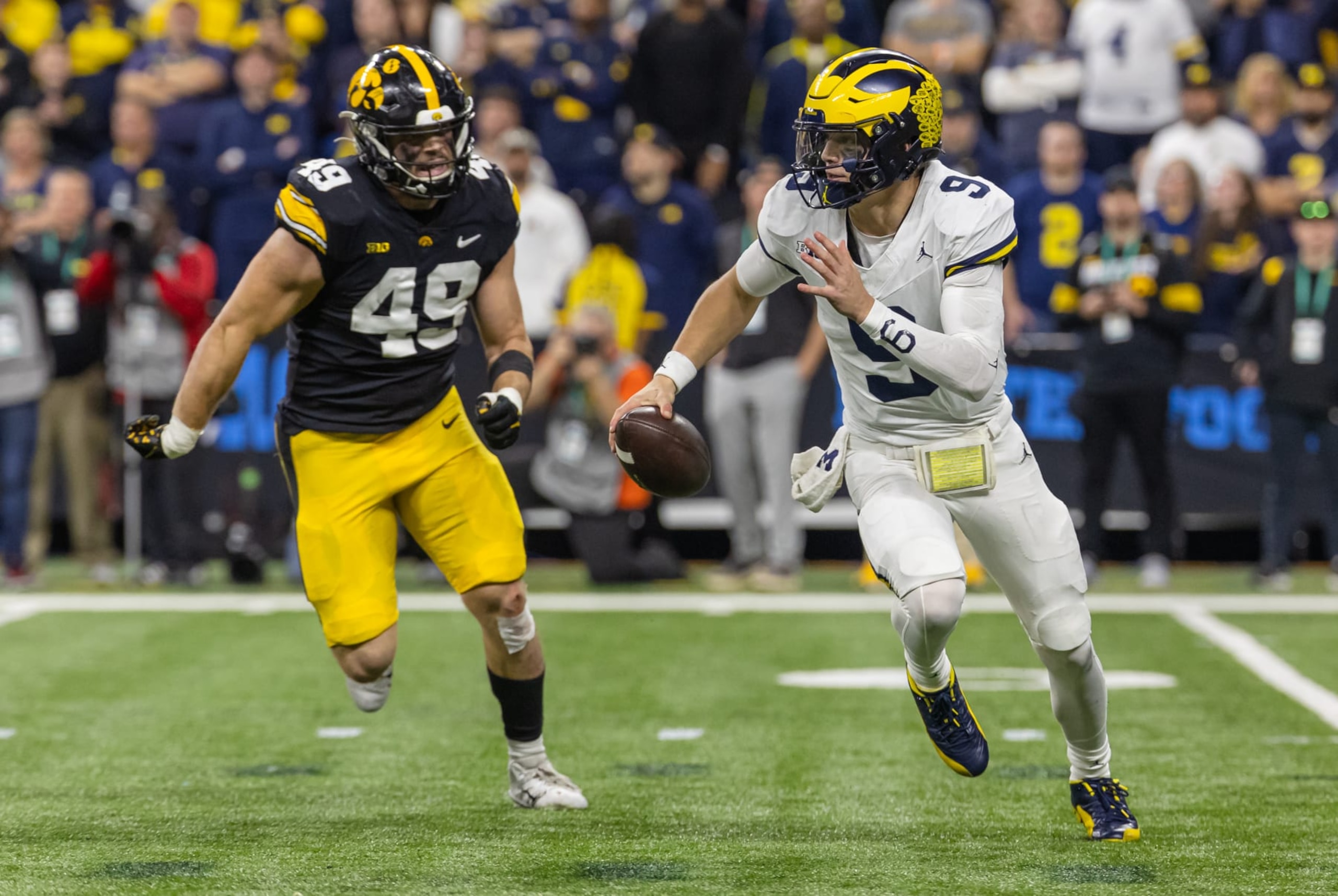 INDIANAPOLIS, INDIANA - DECEMBER 2: J.J. McCarthy #9 of the Michigan Wolverines runs the ball as Ethan Hurkett #49 of the Iowa Hawkeyes pursues during the Big Ten Championship at Lucas Oil Stadium on December 2, 2023 in Indianapolis, Indiana. (Photo by Michael Hickey/Getty Images) 