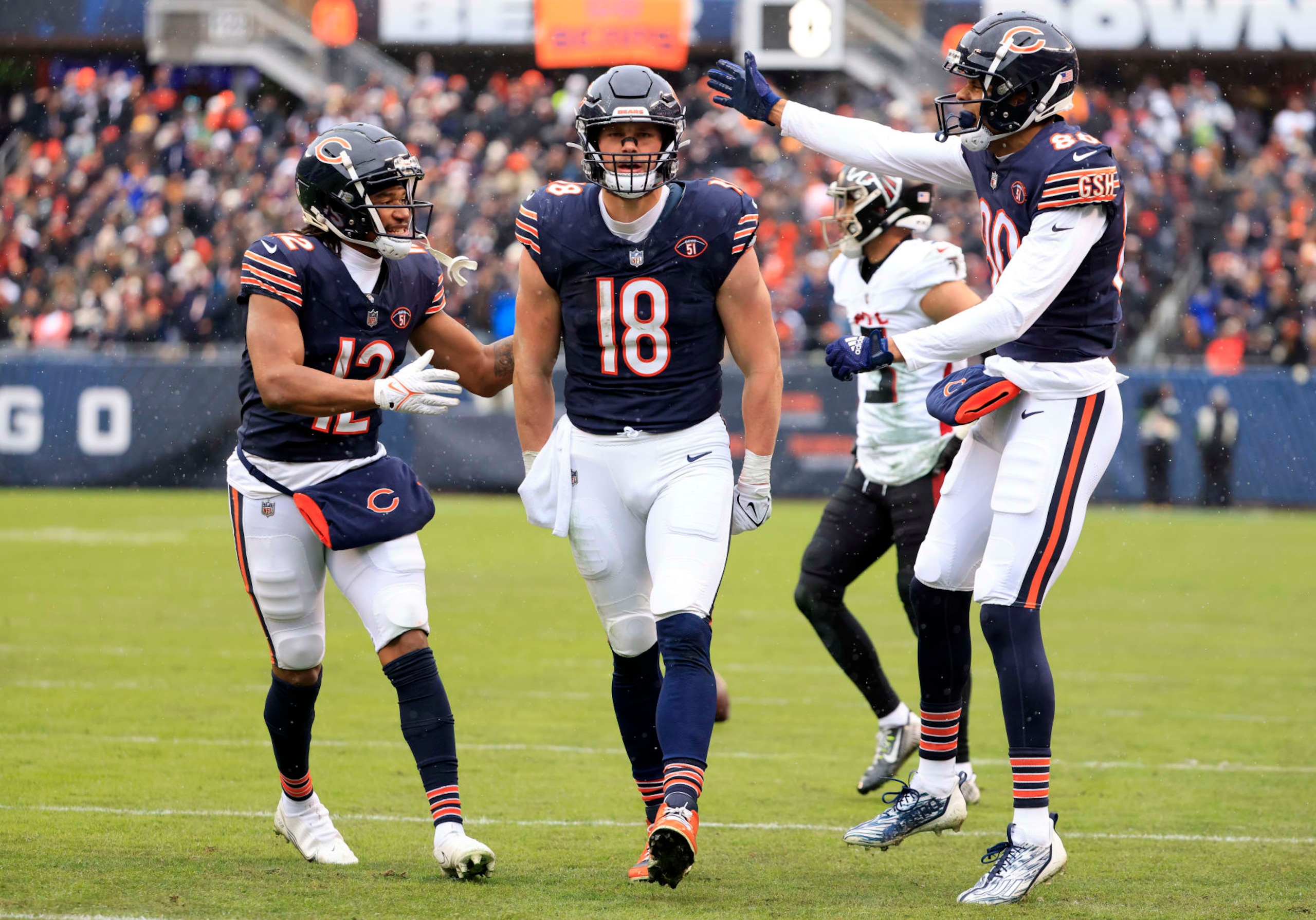 CHICAGO, ILLINOIS - DECEMBER 31: Velus Jones Jr. #12 of the Chicago Bears, Robert Tonyan #18 of the Chicago Bears, and Collin Johnson #80 of the Chicago Bears celebrate after Tonyan's catch during the second quarter against the Atlanta Falcons at Soldier Field on December 31, 2023 in Chicago, Illinois. (Photo by Justin Casterline/Getty Images)