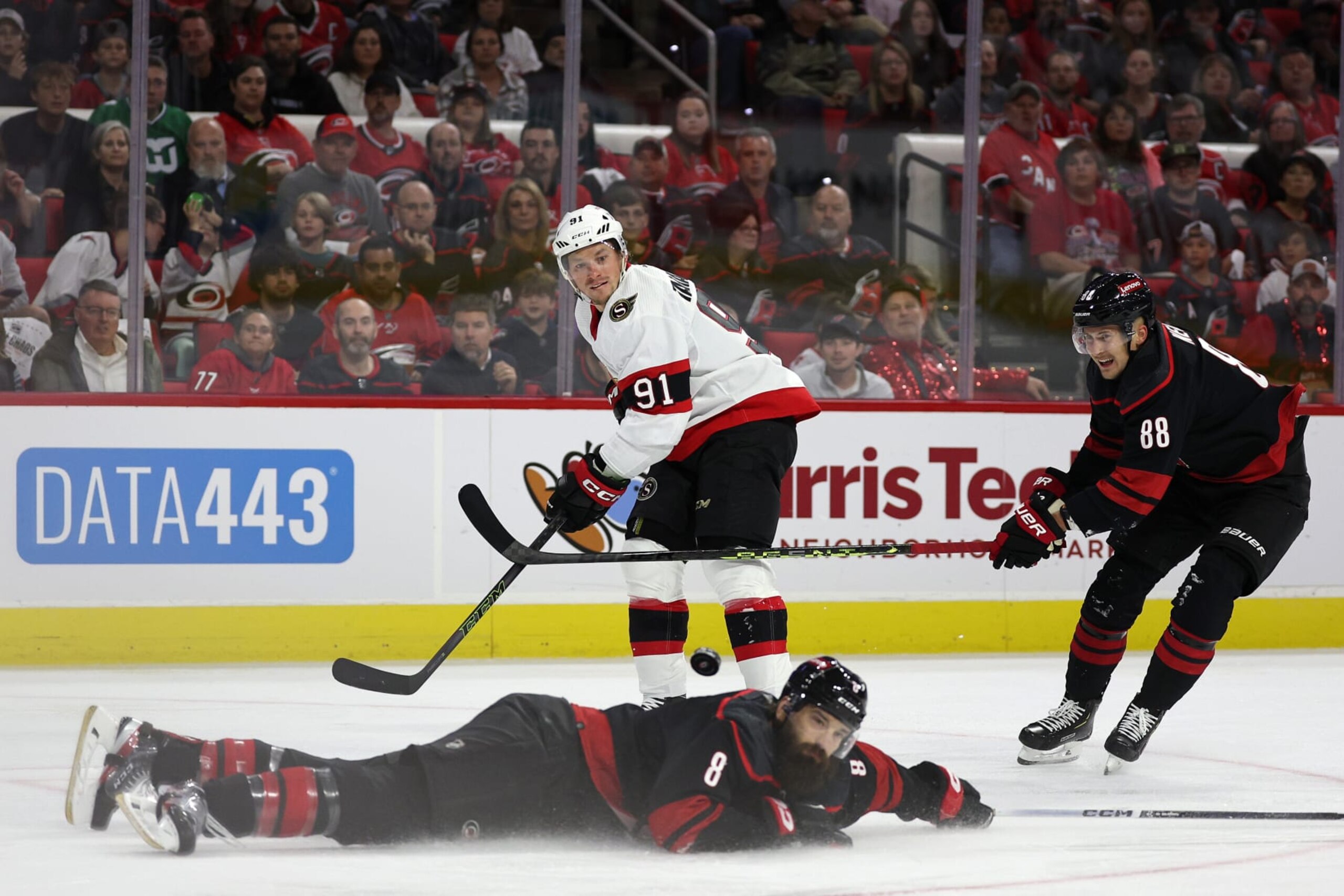 RALEIGH, NORTH CAROLINA - OCTOBER 11: Vladimir Tarasenko #91 of the Ottawa Senators attempts a sauce pass  over Brent Burns #8 of the Carolina Hurricanes during the first period of their game at PNC Arena on October 11, 2023 in Raleigh, North Carolina. (Photo by Jared C. Tilton/Getty Images)