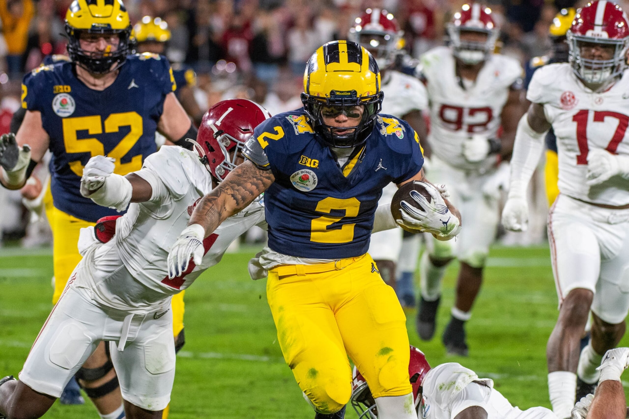 PASADENA, CALIFORNIA - JANUARY 01: Blake Corum #2 of the Michigan Wolverines runs with the ball for yardage away from Kool-Aid McKinstry #1 of the Alabama Crimson Tide during second half of the CFP Semifinal Rose Bowl Game at Rose Bowl Stadium on January 01, 2024 in Pasadena, California. The Michigan Wolverines won the game 27-20 in overtime. (Photo by Aaron J. Thornton/Getty Images)