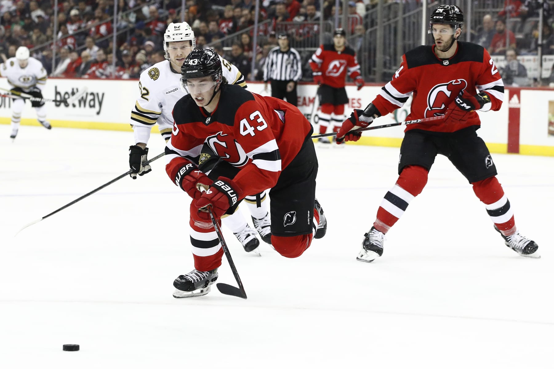 NEWARK, NEW JERSEY - DECEMBER 13: Luke Hughes #43 of the New Jersey Devils chases the puck as Oskar Steen #62 of the Boston Bruins defends during the first period at Prudential Center on December 13, 2023 in Newark, New Jersey. (Photo by Sarah Stier/Getty Images)