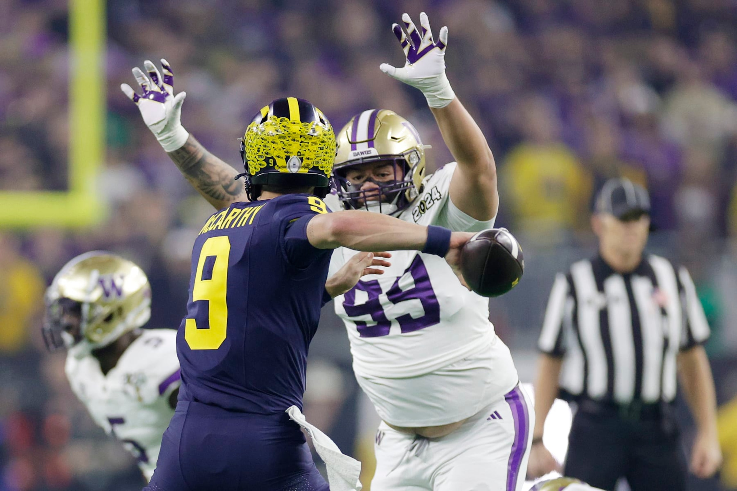 HOUSTON, TEXAS - JANUARY 08: J.J. McCarthy #9 of the Michigan Wolverines throws the ball while under pressure by Faatui Tuitele #99 of the Washington Huskies in the first quarter during the 2024 CFP National Championship game at NRG Stadium on January 08, 2024 in Houston, Texas. (Photo by Carmen Mandato/Getty Images)