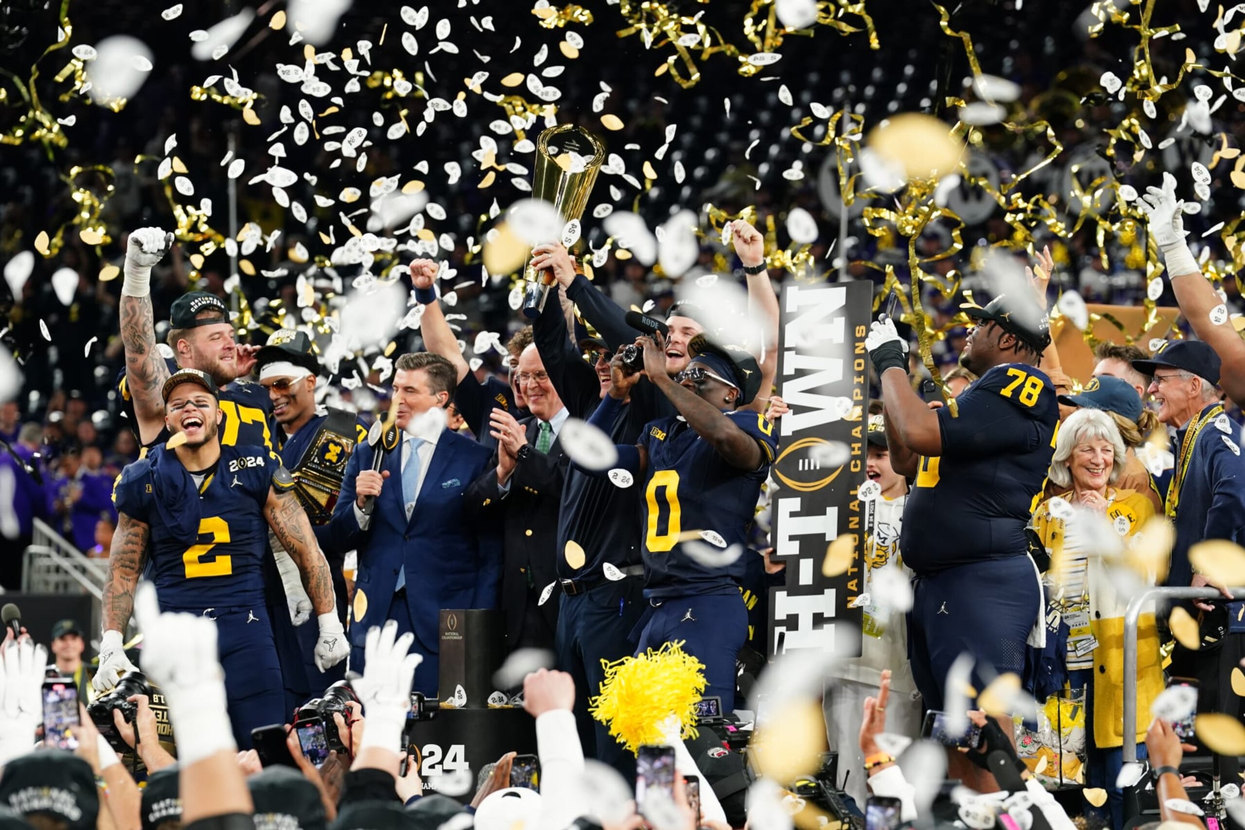 HOUSTON, TX - JANUARY 08: (L-R) RB Blake Corum (2), OL Trevor Keegan (77), DB Will Johnson (2), Head Coach Jim Harbaugh, DB Mike Sainristil (0) and DL Kenneth Grant (78) celebrates with the championship trophy after the Wolverines defeat the Washington Huskies 34-13 in the CFP National Championship game on January 8, 2024, at NRG Stadium in Houston, TX. (Photo by Daniel Dunn/Icon Sportswire via Getty Images)