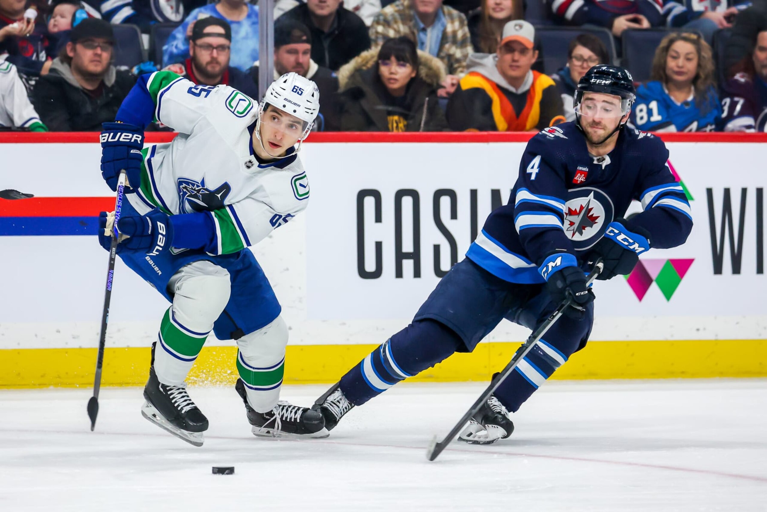 WINNIPEG, CANADA - JANUARY 08: Ilya Mikheyev #65 of the Vancouver Canucks plays the puck away from Neal Pionk #4 of the Winnipeg Jets during second period action at Canada Life Centre on January 08, 2023 in Winnipeg, Manitoba, Canada. (Photo by Jonathan Kozub/NHLI via Getty Images) WINNIPEG, CANADA - JANUARY 08: Ilya Mikheyev #65 of the Vancouver Canucks plays the puck away from Neal Pionk #4 of the Winnipeg Jets during second period action at Canada Life Centre on January 08, 2023 in Winnipeg, Manitoba, Canada. (Photo by Jonathan Kozub/NHLI via Getty Images)