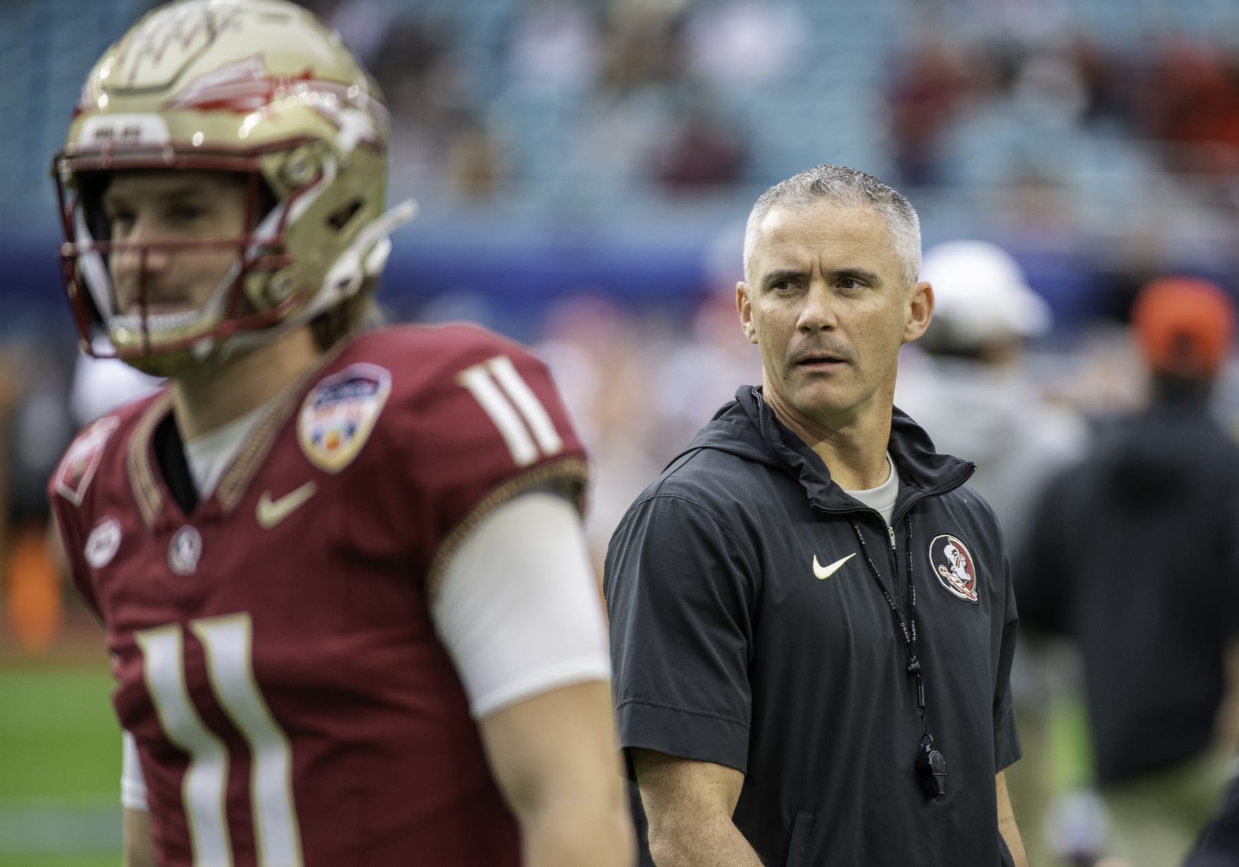 MIAMI GARDENS, FL - DECEMBER 30: Florida State head coach Mike Norvell walks behind Florida State quarterback Brock Glenn (11) as he warms up on the field before the Capital One Orange Bowl college football game between the Georgia Bulldogs and the Florida State Seminoles on December 30, 2023 at the Hard Rock Stadium in Miami Gardens, FL. (Photo by Doug Murray/Icon Sportswire via Getty Images)