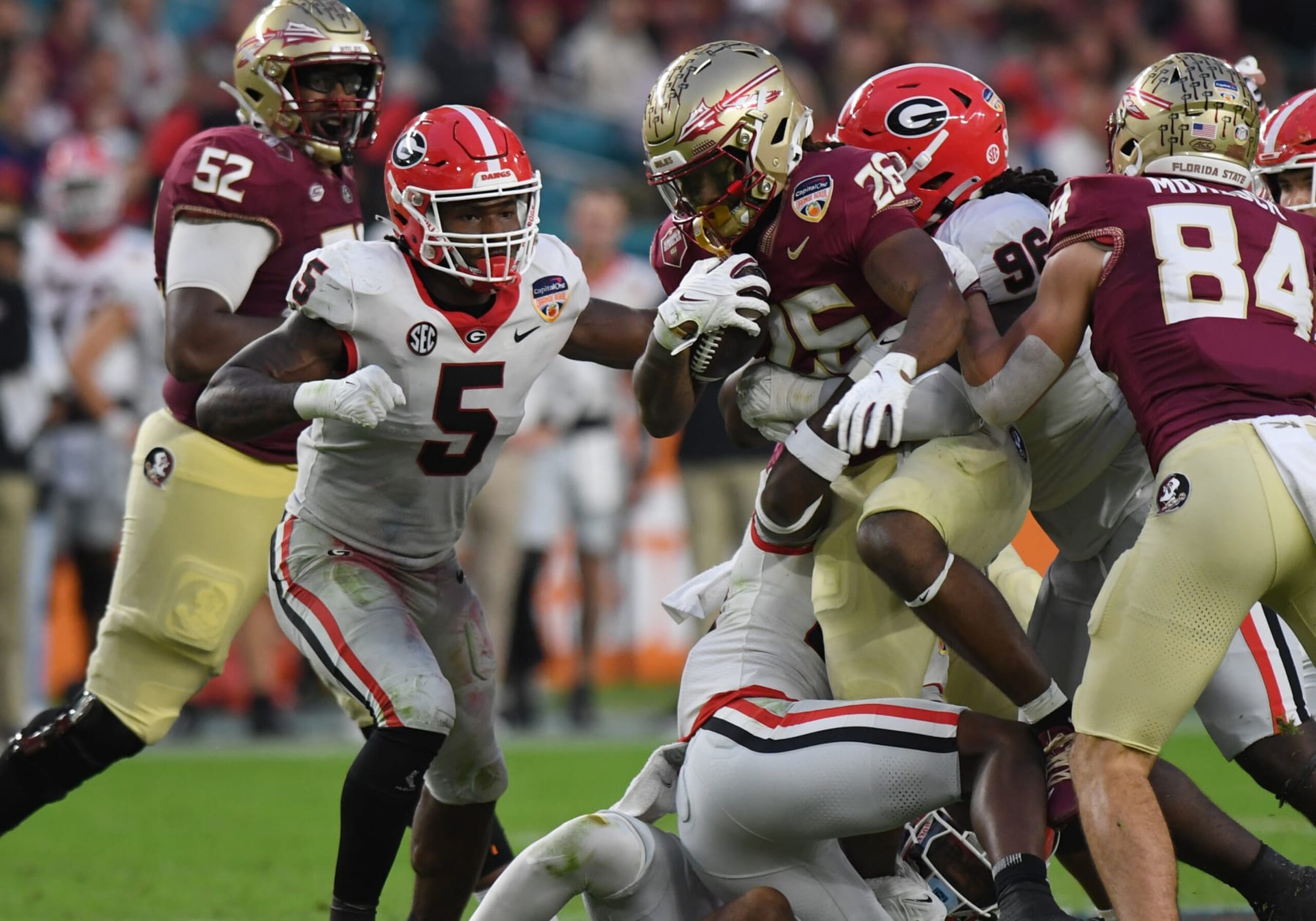 MIAMI GARDENS, FL - DECEMBER 30: Florida State Seminoles Running Back Caziah Holmes (26) rushes the ball as Georgia Bulldogs Linebacker Raylen Wilson (5) defends during the Capital One Orange Bowl between the Georgia Bulldogs and the Florida State Seminoles on December 30, 2023, at Hard Rock Stadium in Miami Gardens, FL. (Photo by Jeffrey Vest/Icon Sportswire via Getty Images)