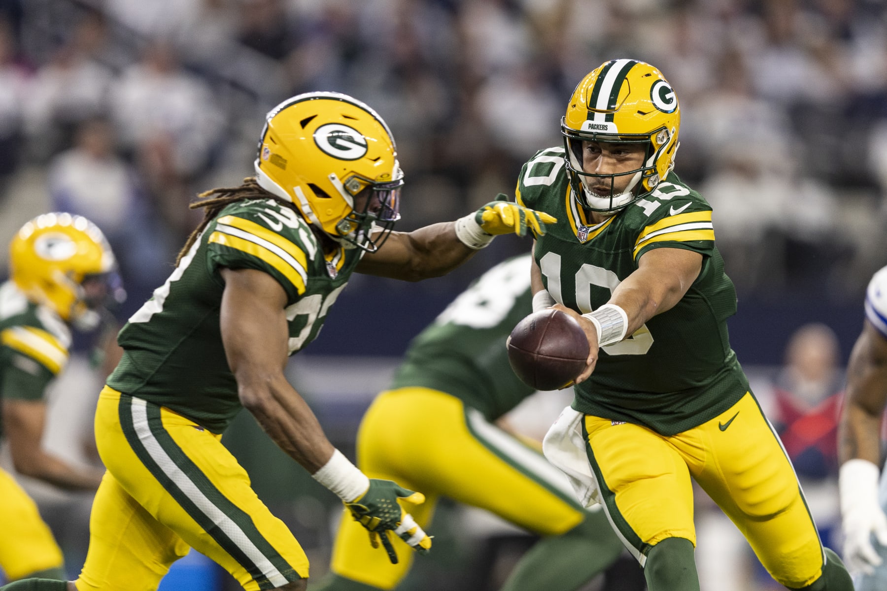 ARLINGTON, TEXAS - JANUARY 14: Jordan Love #10 of the Green Bay Packers hands the ball off to Aaron Jones #33 of the Green Bay Packers during an NFL wild-card playoff football game between the Dallas Cowboys and the Green Bay Packers at AT&T Stadium on January 14, 2024 in Arlington, Texas. (Photo by Michael Owens/Getty Images)