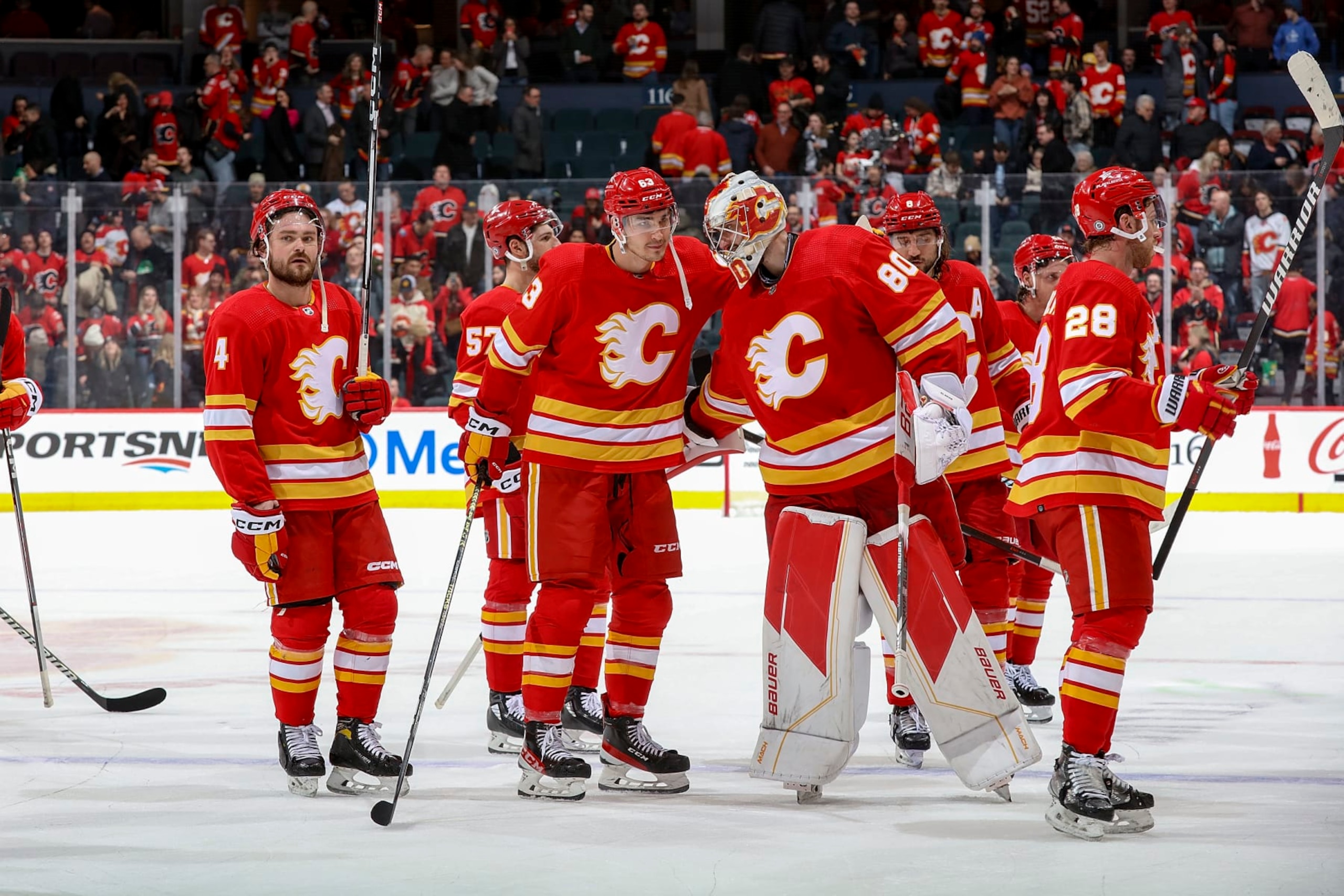 CALGARY, AB - JANUARY 16: Adam Ruzicka #63 and Daniel Vladar #80 of the Calgary Flames celebrate on ice after a win in OT against the Arizona Coyotes at Scotiabank Saddledome on January 16, 2024 in Calgary, Alberta, Canada. (Photo by Gerry Thomas/NHLI via Getty Images)