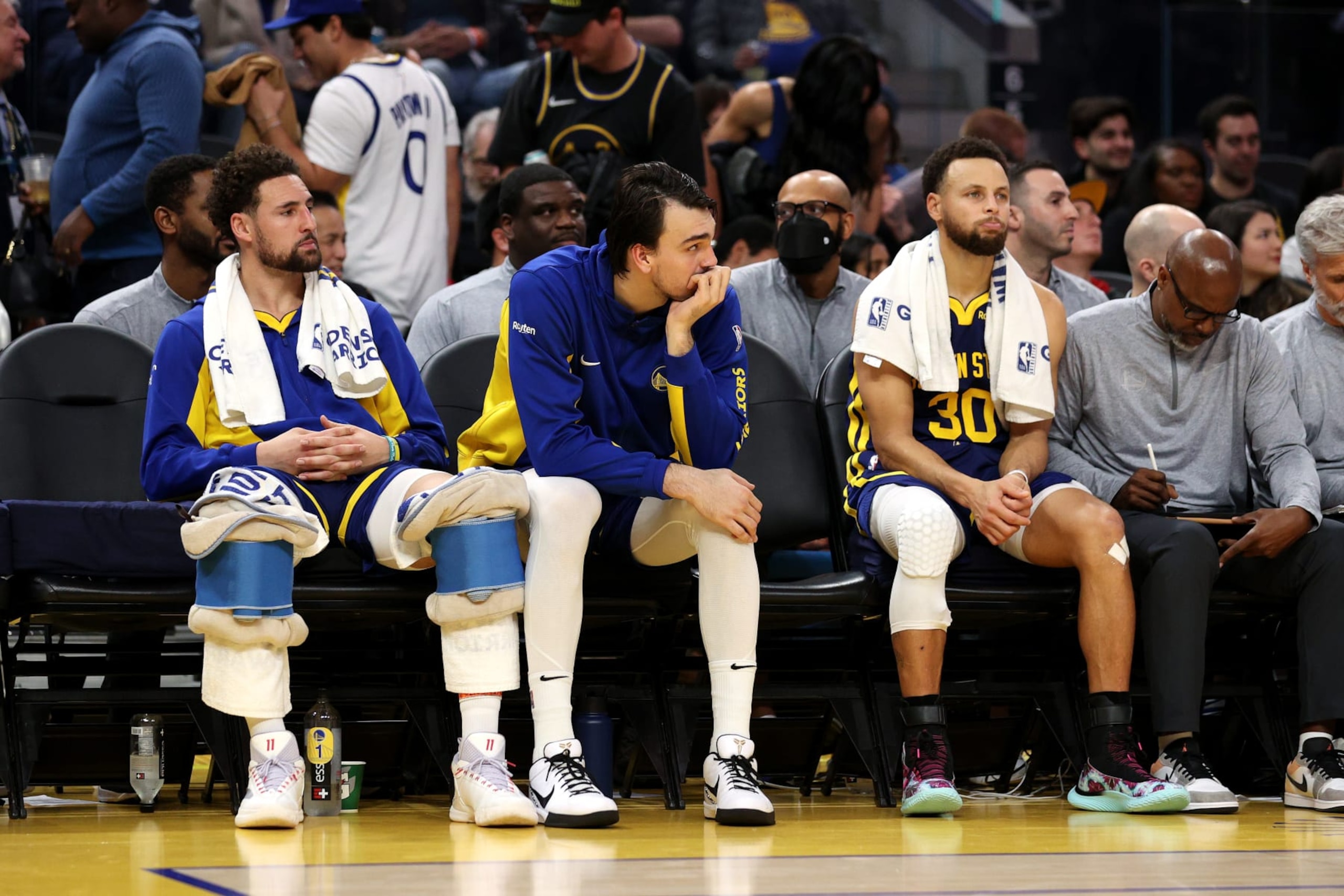 SAN FRANCISCO, CALIFORNIA - DECEMBER 28: Klay Thompson #11, Dario Saric #20 and Stephen Curry #30 of the Golden State Warriors sit on the bench during the closing minutes of their loss to the Miami Heat in the second half at Chase Center on December 28, 2023 in San Francisco, California. NOTE TO USER: User expressly acknowledges and agrees that, by downloading and or using this photograph, User is consenting to the terms and conditions of the Getty Images License Agreement.  (Photo by Ezra Shaw/Getty Images)