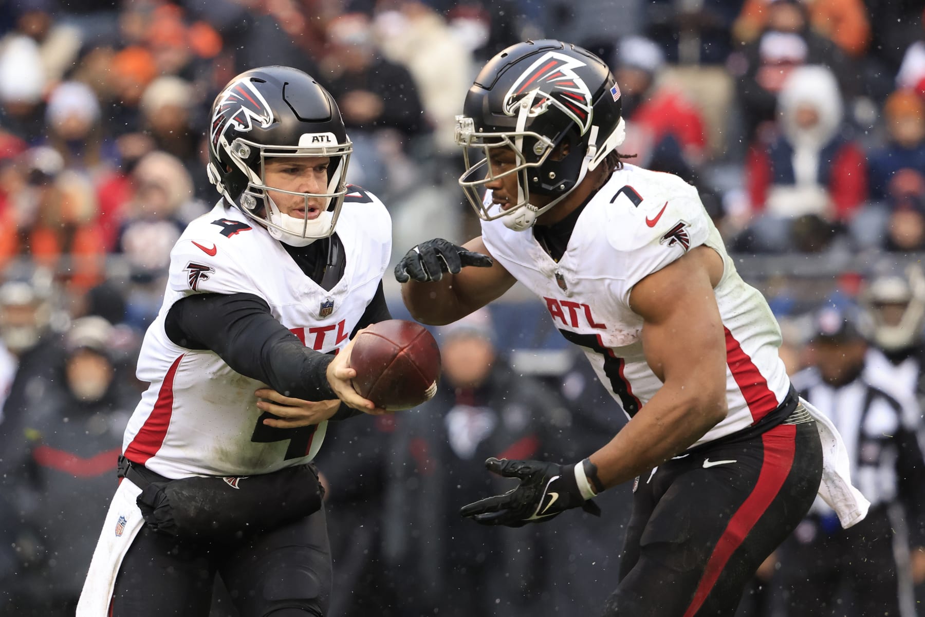 CHICAGO, ILLINOIS - DECEMBER 31: Taylor Heinicke #4 of the Atlanta Falcons hands the ball off to Bijan Robinson #7 in the game against the Atlanta Falcons at Soldier Field on December 31, 2023 in Chicago, Illinois. (Photo by Justin Casterline/Getty Images)