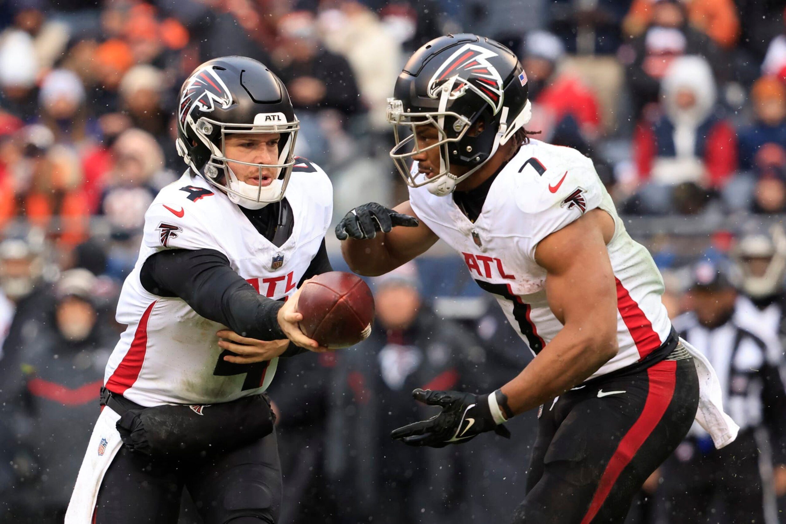 CHICAGO, ILLINOIS - DECEMBER 31: Taylor Heinicke #4 of the Atlanta Falcons hands the ball off to Bijan Robinson #7 in the game against the Atlanta Falcons at Soldier Field on December 31, 2023 in Chicago, Illinois. (Photo by Justin Casterline/Getty Images)
