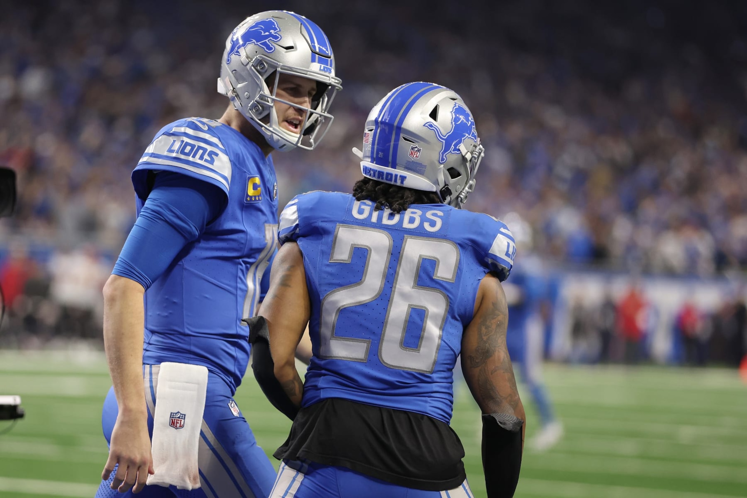 DETROIT, MICHIGAN - JANUARY 21: Jahmyr Gibbs #26 of the Detroit Lions celebrates a touchdown with Jared Goff #16 during the fourth quarter of the NFC Divisional Playoff game against the Tampa Bay Buccaneers at Ford Field on January 21, 2024 in Detroit, Michigan. (Photo by Gregory Shamus/Getty Images)
