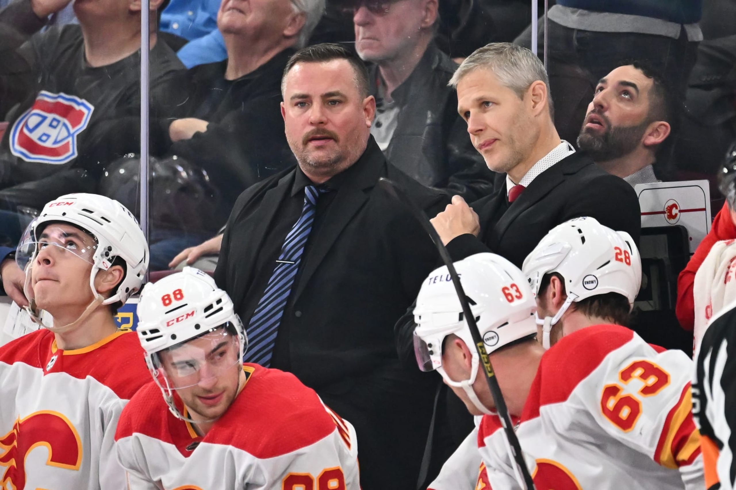 MONTREAL, CANADA - NOVEMBER 14:  Assistant coaches Marc Savard (L) and Cail MacLean (R) of the Calgary Flames handle bench duties during the third period against the Montreal Canadiens at the Bell Centre on November 14, 2023 in Montreal, Quebec, Canada.  The Calgary Flames defeated the Montreal Canadiens 2-1.  (Photo by Minas Panagiotakis/Getty Images)