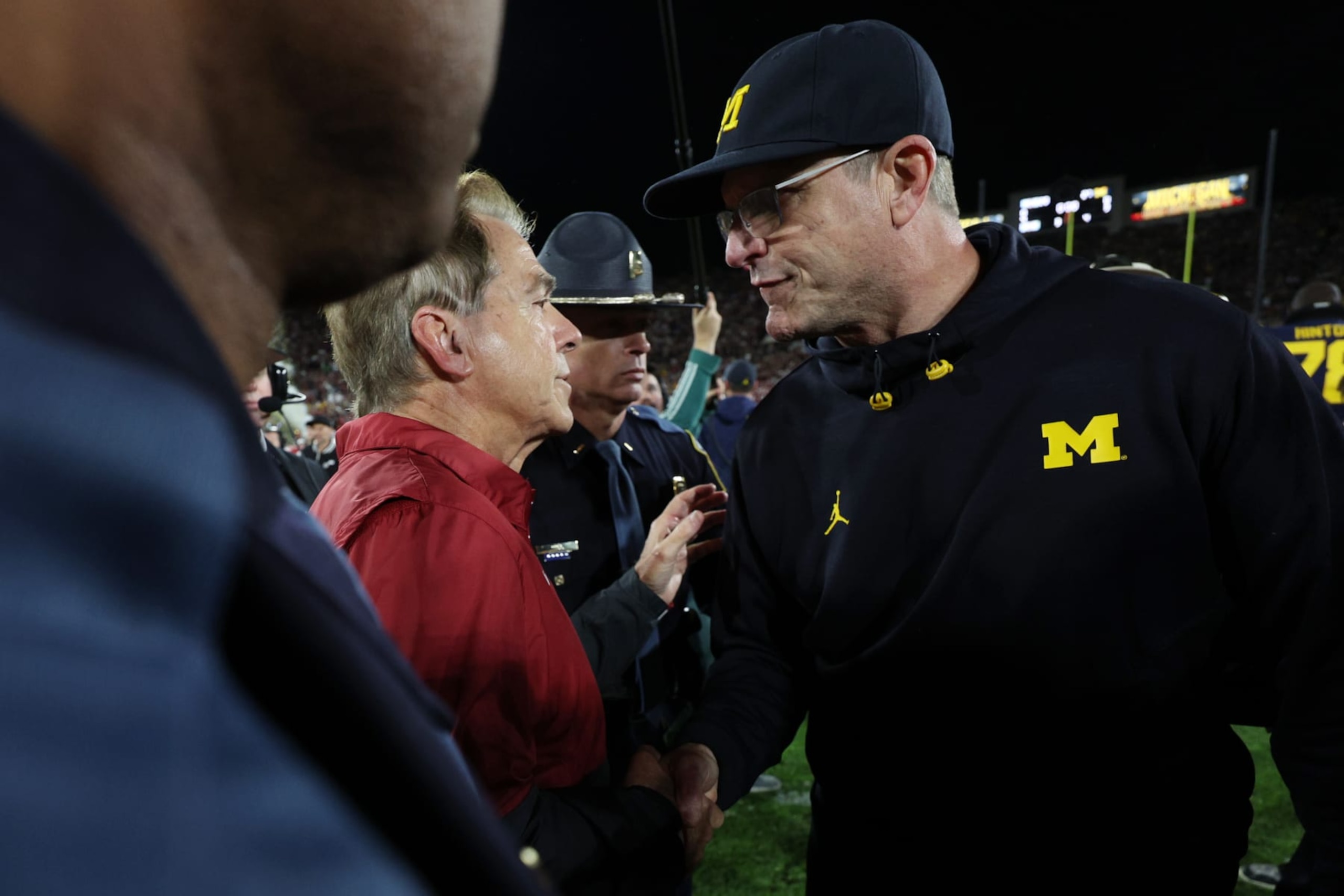 PASADENA, CALIFORNIA - JANUARY 01: Head coach Nick Saban of the Alabama Crimson Tide and head coach Jim Harbaugh of the Michigan Wolverines meet after the Wolverines beat the Crimson Tide 27-20 in overtime to win the CFP Semifinal Rose Bowl Game at Rose Bowl Stadium on January 01, 2024 in Pasadena, California. (Photo by Harry How/Getty Images)