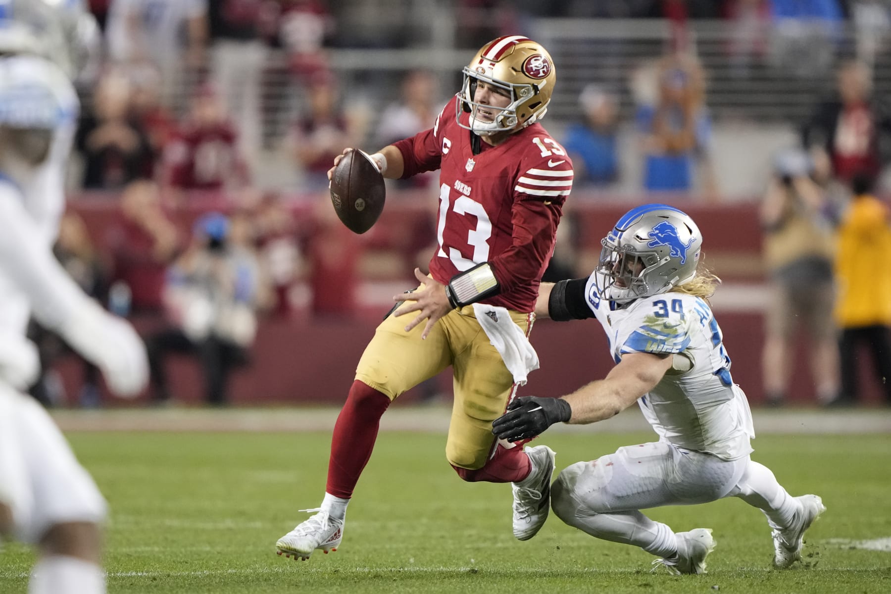 SANTA CLARA, CALIFORNIA - JANUARY 28: Brock Purdy #13 of the San Francisco 49ers avoids a tackle by Alex Anzalone #34 of the Detroit Lions during the fourth quarter in the NFC Championship Game at Levi's Stadium on January 28, 2024 in Santa Clara, California. (Photo by Thearon W. Henderson/Getty Images)