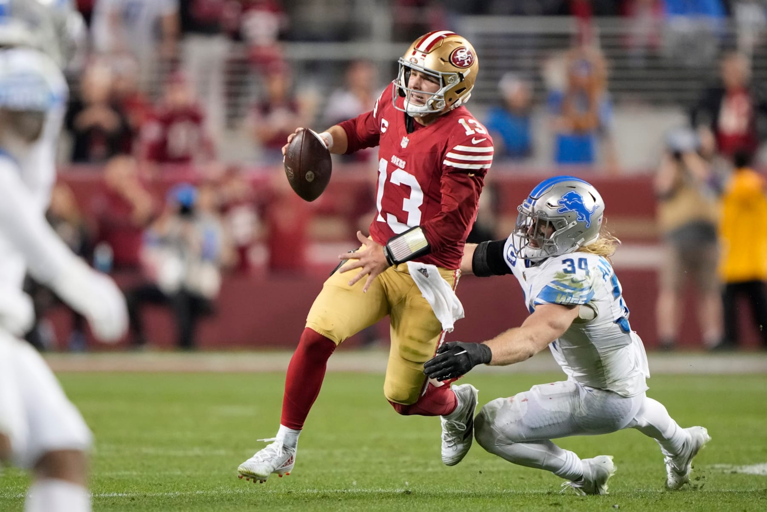 SANTA CLARA, CALIFORNIA - JANUARY 28: Brock Purdy #13 of the San Francisco 49ers avoids a tackle by Alex Anzalone #34 of the Detroit Lions during the fourth quarter in the NFC Championship Game at Levi's Stadium on January 28, 2024 in Santa Clara, California. (Photo by Thearon W. Henderson/Getty Images)