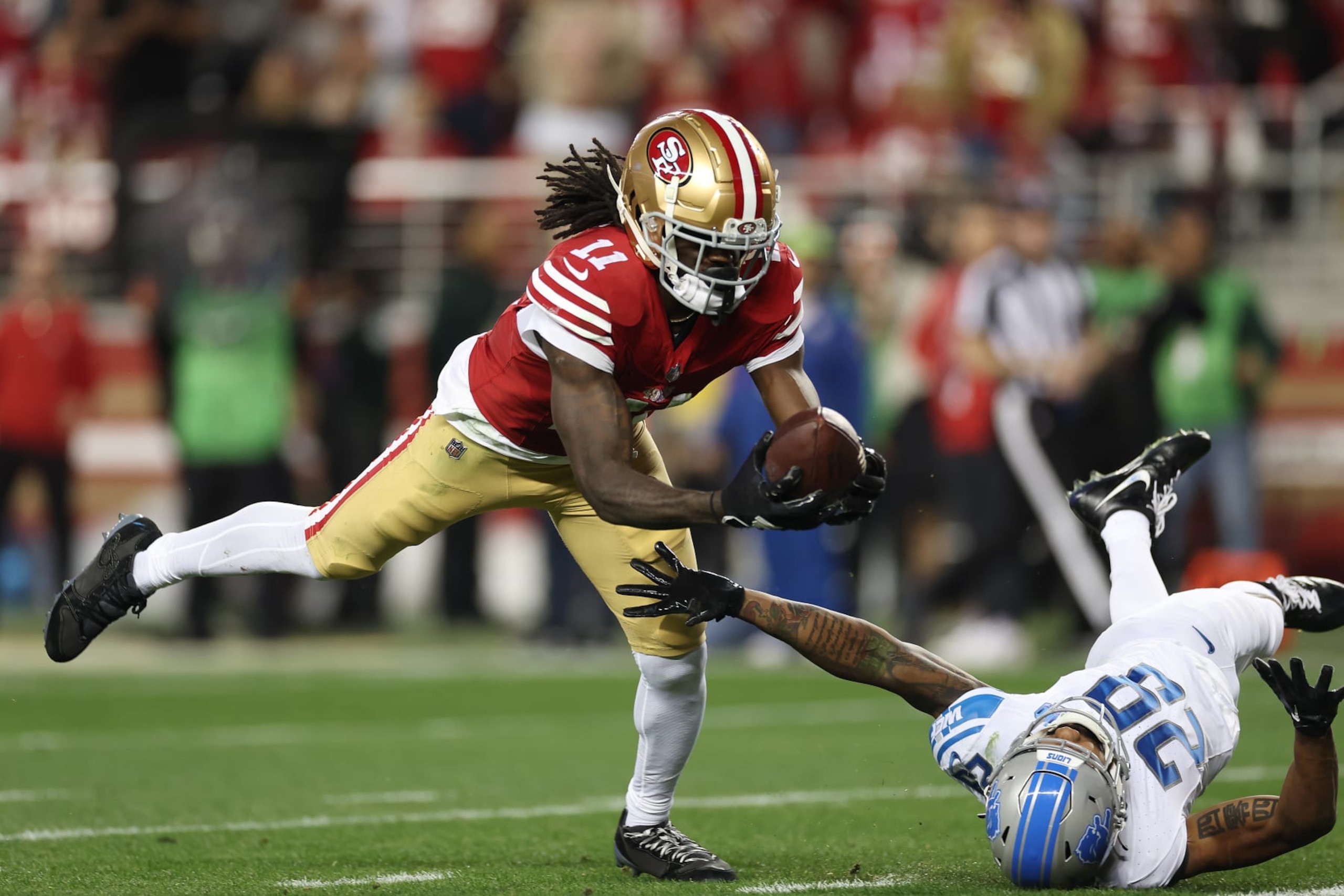SANTA CLARA, CALIFORNIA - JANUARY 28: Brandon Aiyuk #11 of the San Francisco 49ers catches a pass that was tipped by Kindle Vildor #29 of the Detroit Lions during the third quarter in the NFC Championship Game at Levi's Stadium on January 28, 2024 in Santa Clara, California. (Photo by Ezra Shaw/Getty Images)