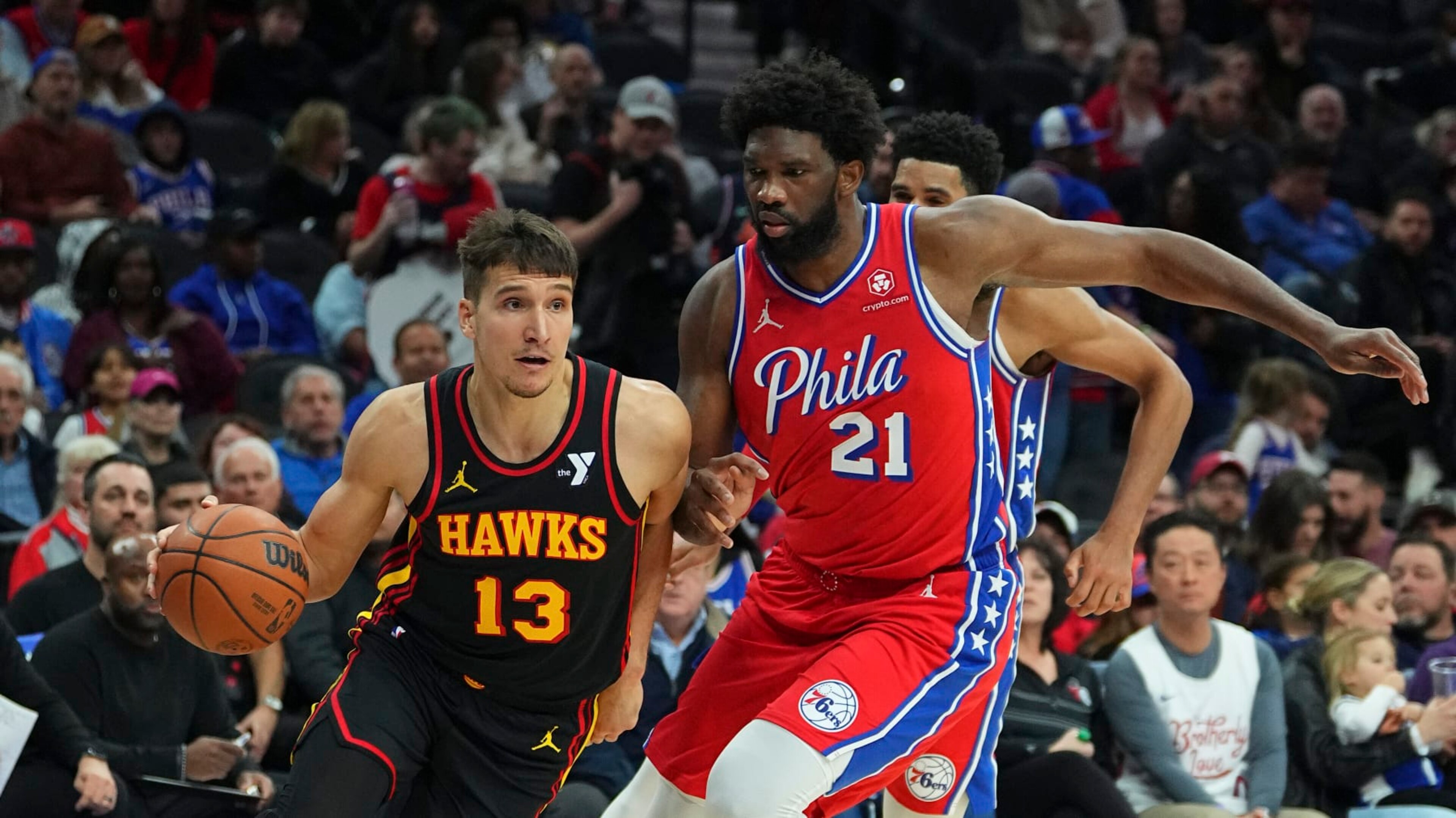 PHILADELPHIA, PENNSYLVANIA - DECEMBER 8: Bogdan Bogdanovic #13 of the Atlanta Hawks drives to the basket against Joel Embiid #21 of the Philadelphia 76ers at the Wells Fargo Center on December 8, 2023 in Philadelphia, Pennsylvania. NOTE TO USER: User expressly acknowledges and agrees that, by downloading and or using this photograph, User is consenting to the terms and conditions of the Getty Images License Agreement. (Photo by Mitchell Leff/Getty Images)