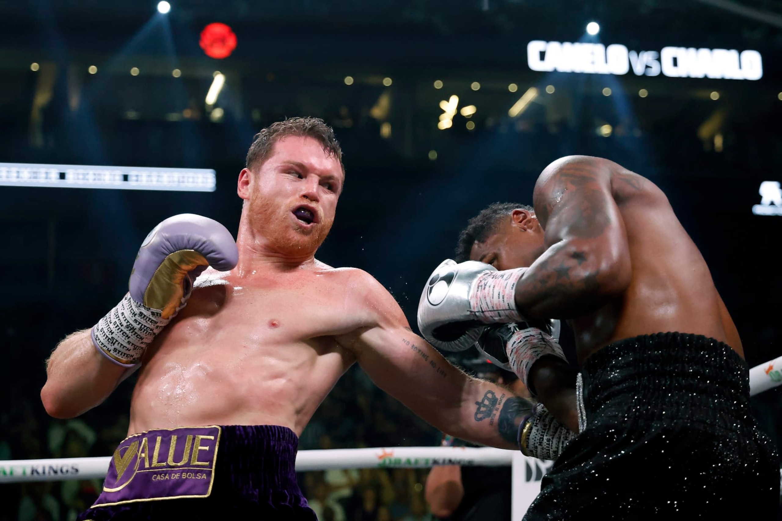 LAS VEGAS, NEVADA - SEPTEMBER 30:   Saul "Canelo" Alvarez of Mexico (purple/gold trunks) trades punches with Jermell Charlo (black trunks) during their super middleweight title fight at T-Mobile Arena on September 30, 2023 in Las Vegas, Nevada.  (Photo by Sarah Stier/Getty Images)