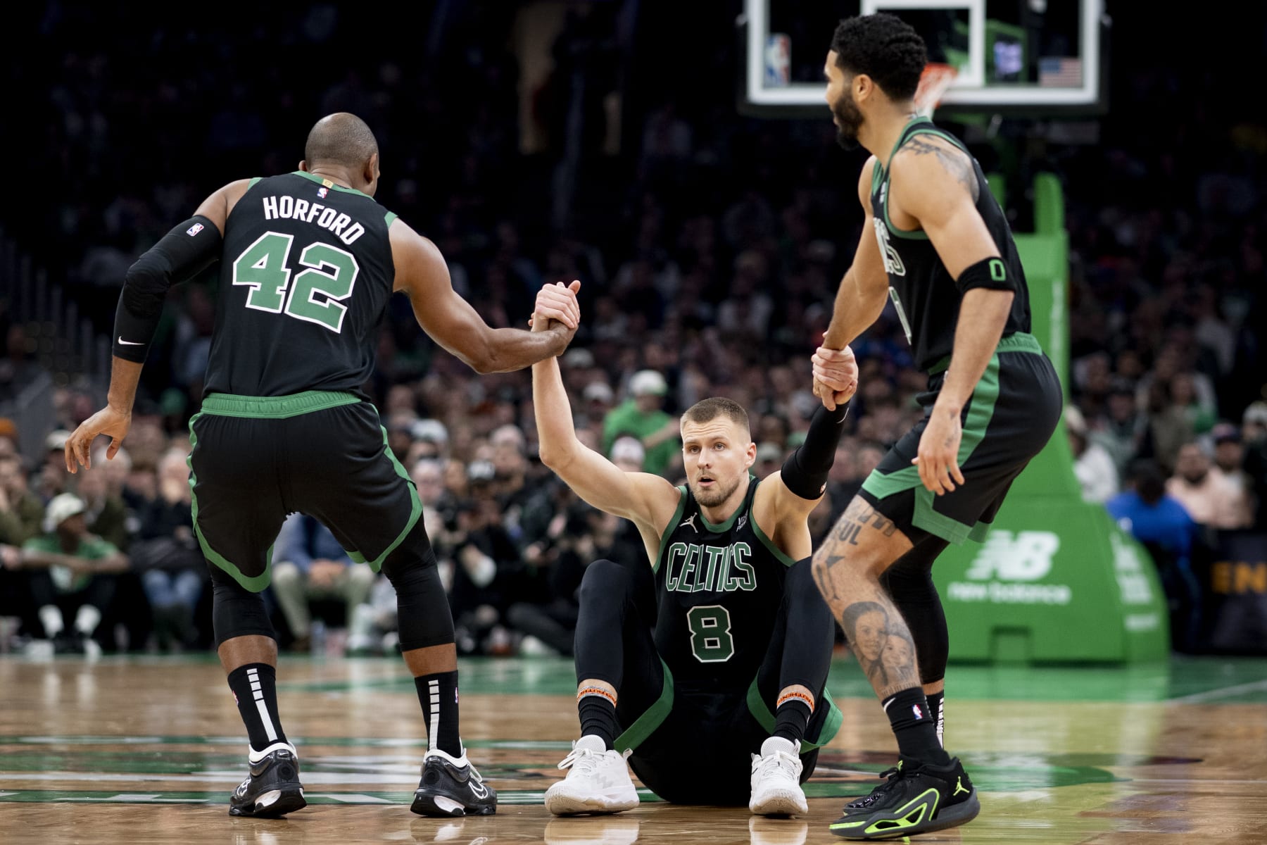 BOSTON, MASSACHUSETTS - NOVEMBER 13: Al Horford #42 of the Boston Celtics and Jayson Tatum #0 of the Boston Celtics help Kristaps Porzingis #8 of the Boston Celtics off the ground against the New York Knicks at TD Garden on November 13, 2023 in Boston, Massachusetts. NOTE TO USER: User expressly acknowledges and agrees that, by downloading and or using this photograph, User is consenting to the terms and conditions of the Getty Images License Agreement. (Photo by Maddie Malhotra/Getty Images)