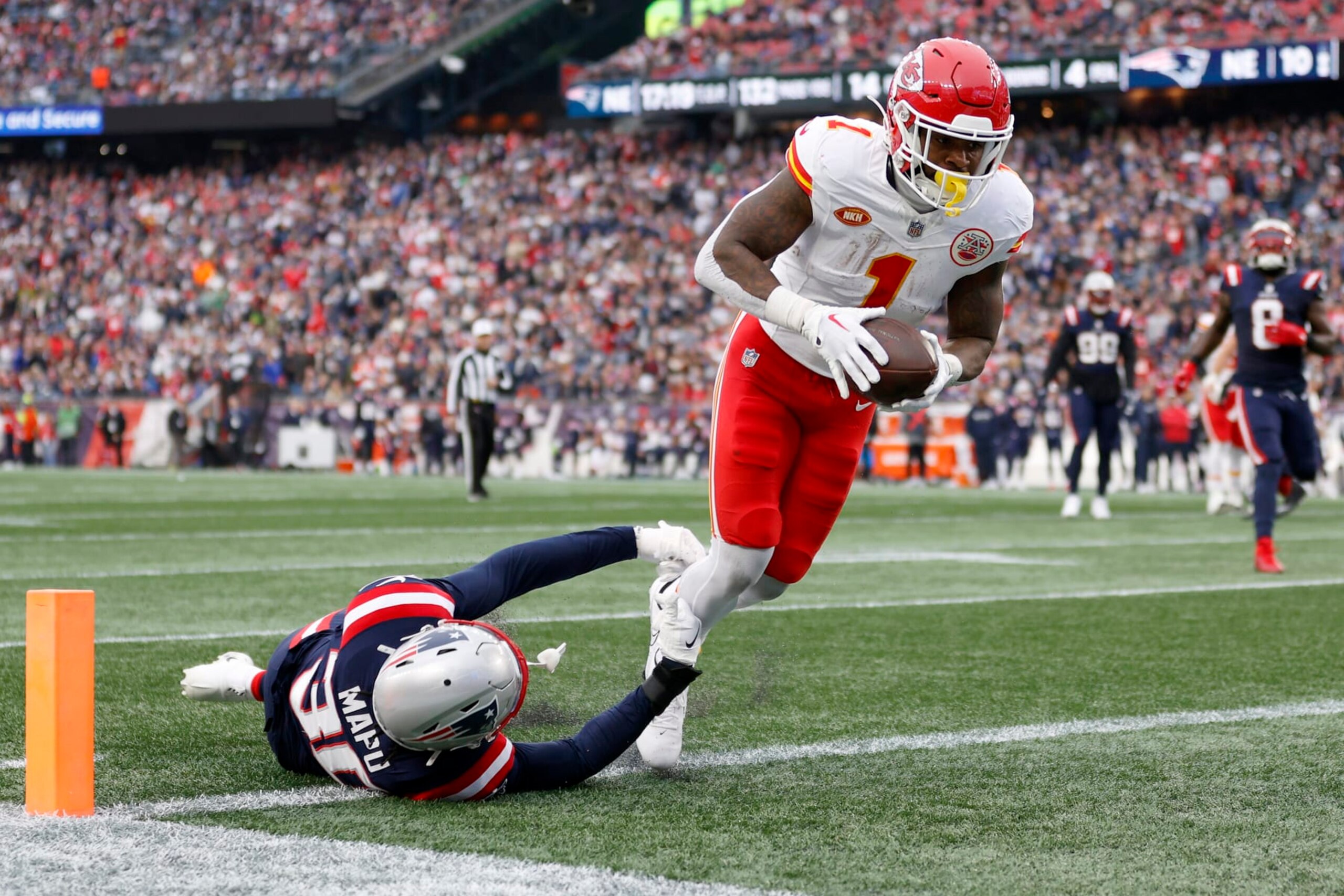 FOXBOROUGH, MASSACHUSETTS - DECEMBER 17: Jerick McKinnon #1 of the Kansas City Chiefs dives over Marte Mapu #30 of the New England Patriots while scoring a receiving touchdown during the second quarter at Gillette Stadium on December 17, 2023 in Foxborough, Massachusetts. (Photo by Sarah Stier/Getty Images)