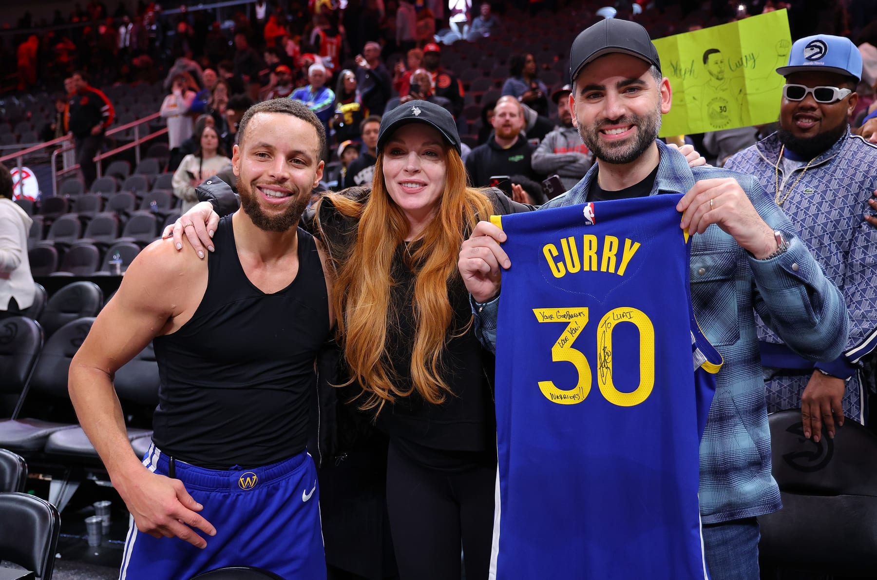 ATLANTA, GEORGIA - FEBRUARY 03:  Stephen Curry #30 of the Golden State Warriors poses with actress Lindsay Lohan and her husband Bader Shammas after giving them his jersey in their 141-134 overtime loss to the Atlanta Hawks at State Farm Arena on February 03, 2024 in Atlanta, Georgia.  NOTE TO USER: User expressly acknowledges and agrees that, by downloading and/or using this photograph, user is consenting to the terms and conditions of the Getty Images License Agreement.  (Photo by Kevin C. Cox/Getty Images)