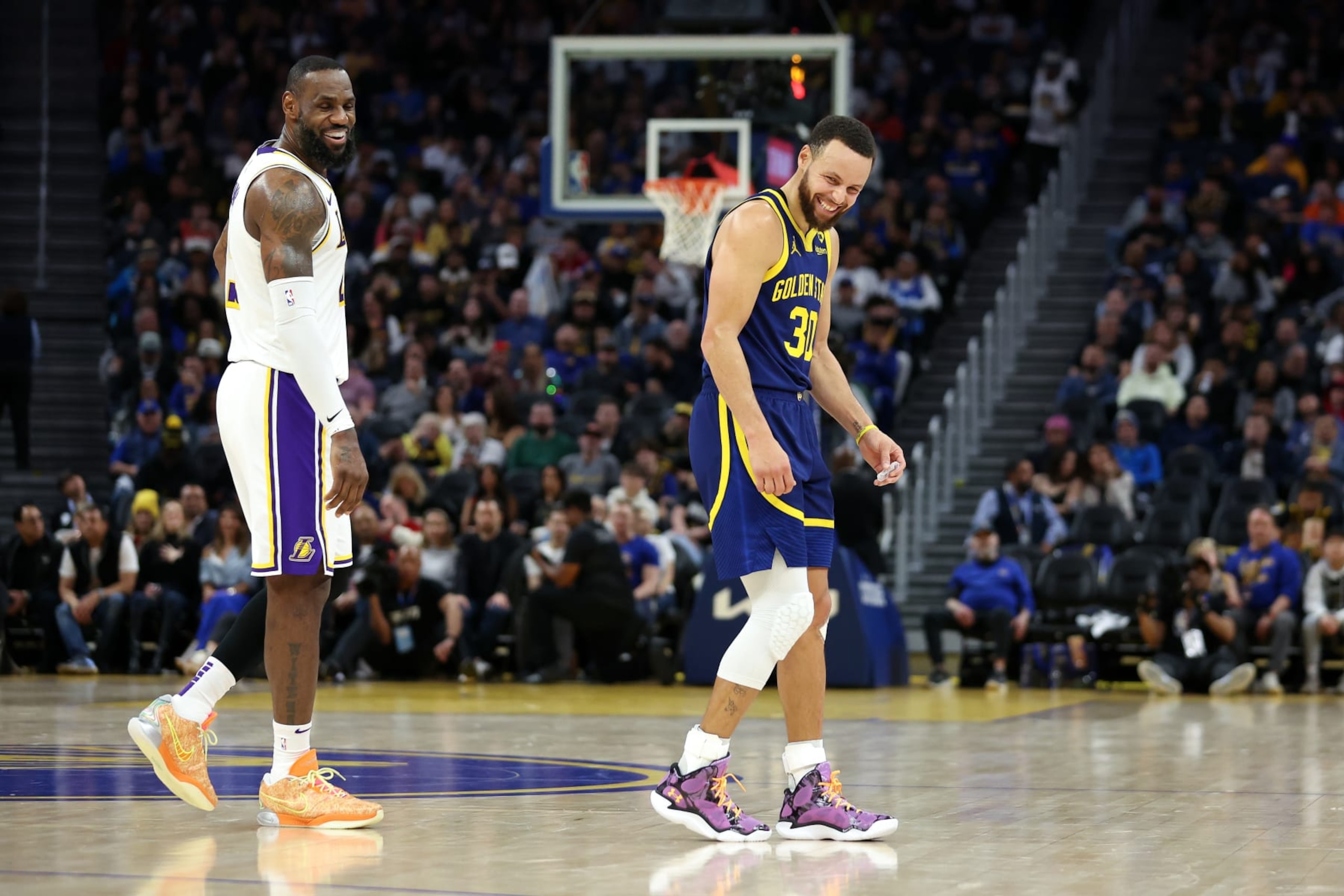 SAN FRANCISCO, CALIFORNIA - JANUARY 27: LeBron James #23 of the Los Angeles Lakers and Stephen Curry #30 of the Golden State Warriors make each other laugh during a stop in play in the first half at Chase Center on January 27, 2024 in San Francisco, California. NOTE TO USER: User expressly acknowledges and agrees that, by downloading and or using this photograph, User is consenting to the terms and conditions of the Getty Images License Agreement.  (Photo by Ezra Shaw/Getty Images)