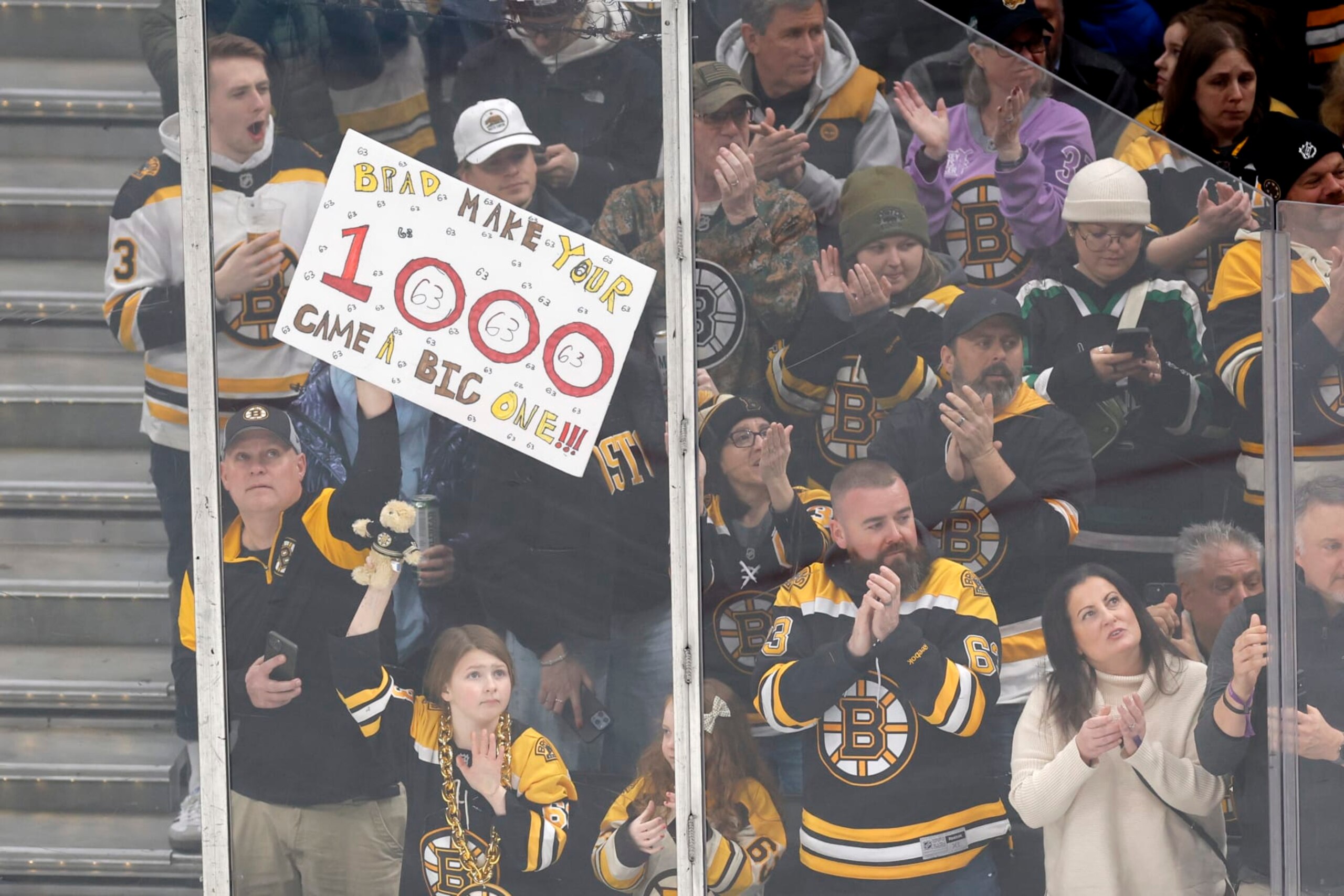 Boston, MA - February 13: A Boston Bruins fan holds up a sign celebrating Brad Marchand's 1,000th game with the team. The Bruins lost to the Tampa Bay Lightning, 3-2, in a shootout. (Photo by Danielle Parhizkaran/The Boston Globe via Getty Images)