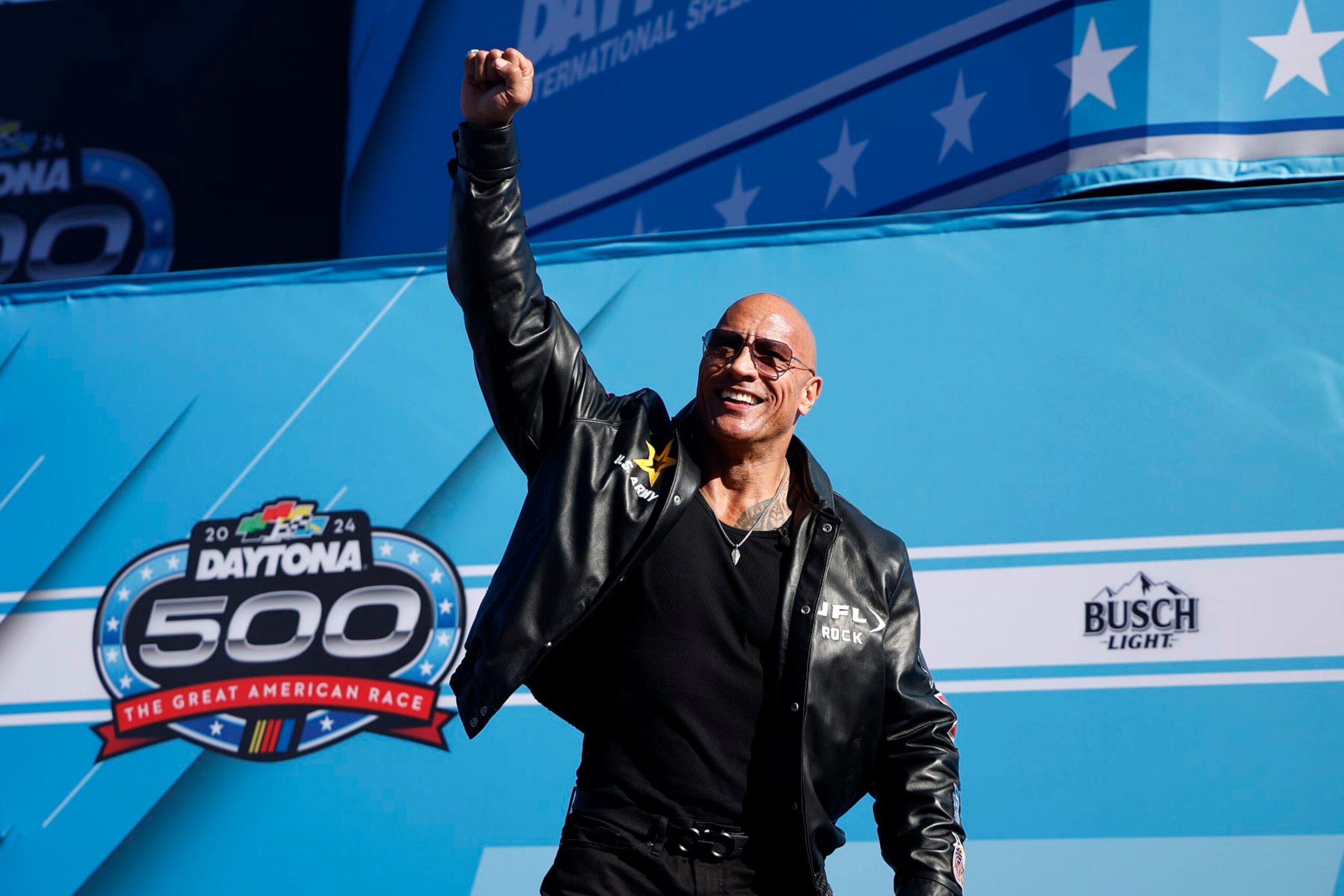 DAYTONA BEACH, FLORIDA - FEBRUARY 19: Grand Marshal Dwayne “The Rock” Johnson waves to fans as he walks onstage during pre-race ceremonies prior to the NASCAR Cup Series Daytona 500 at Daytona International Speedway on February 19, 2024 in Daytona Beach, Florida. (Photo by James Gilbert/Getty Images)