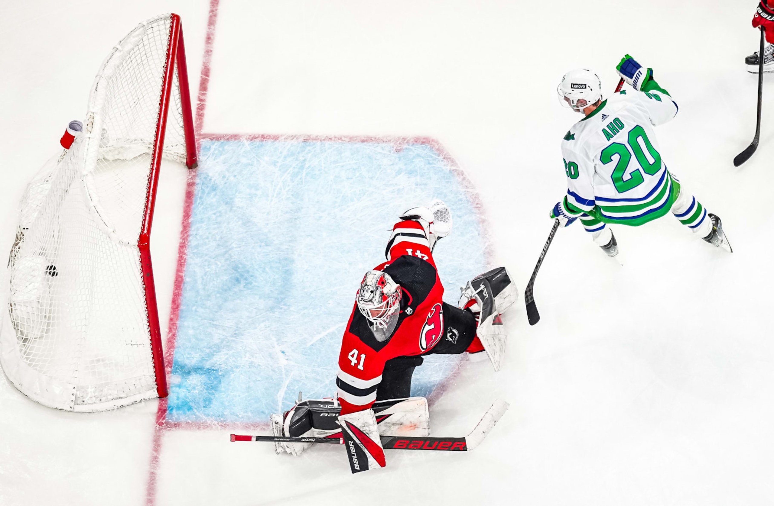 RALEIGH, NORTH CAROLINA - FEBRUARY 10: Sebastian Aho #20 of the Carolina Hurricanes scores the game winning goal against Vitek Vanecek #41 of the New Jersey Devils in overtime at PNC Arena on February 10, 2024 in Raleigh, North Carolina. (Photo by Josh Lavallee/NHLI via Getty Images)