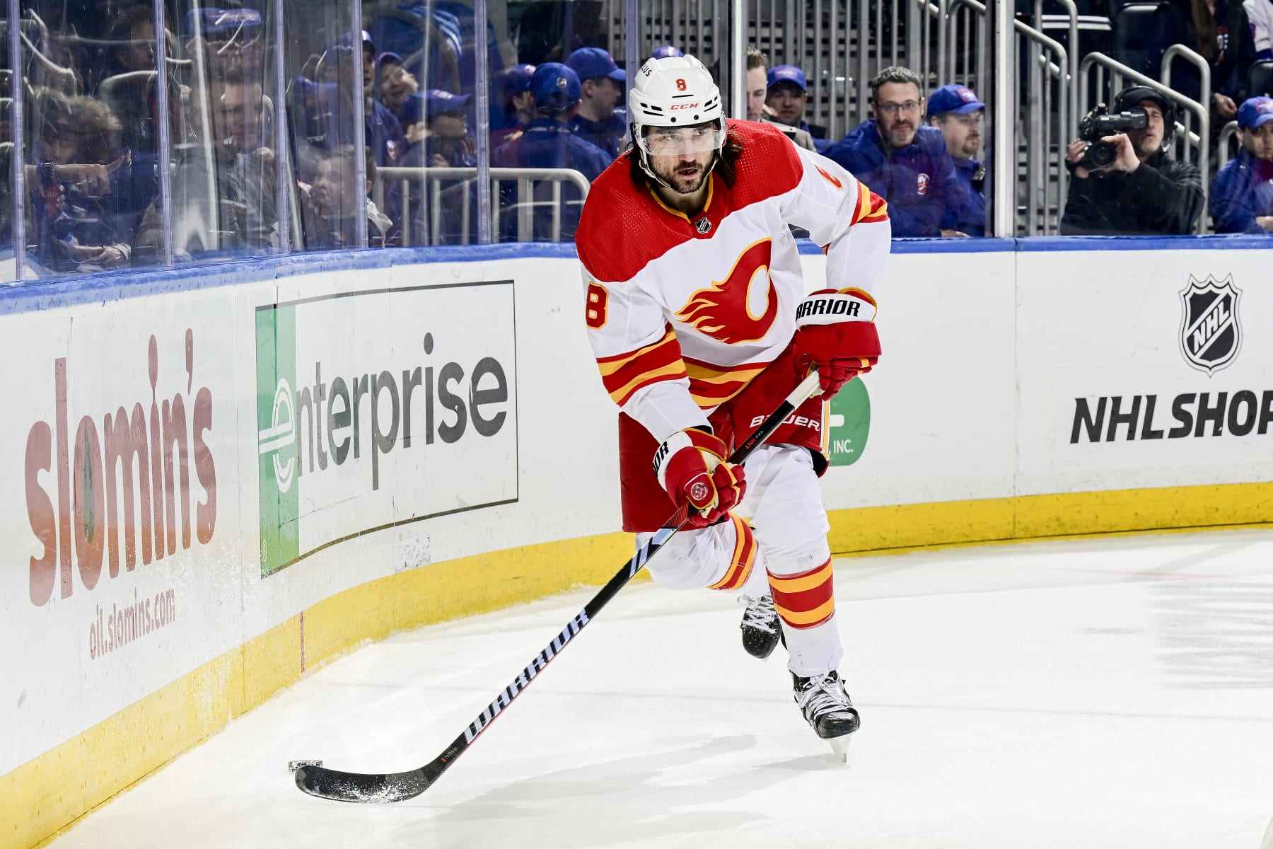 ELMONT, NEW YORK - FEBRUARY 10:  Chris Tanev #8 of the Calgary Flames carries the puck against the New York Islanders at UBS Arena on February 10, 2024 in Elmont, New York. (Photo by Steven Ryan/NHLI via Getty Images)