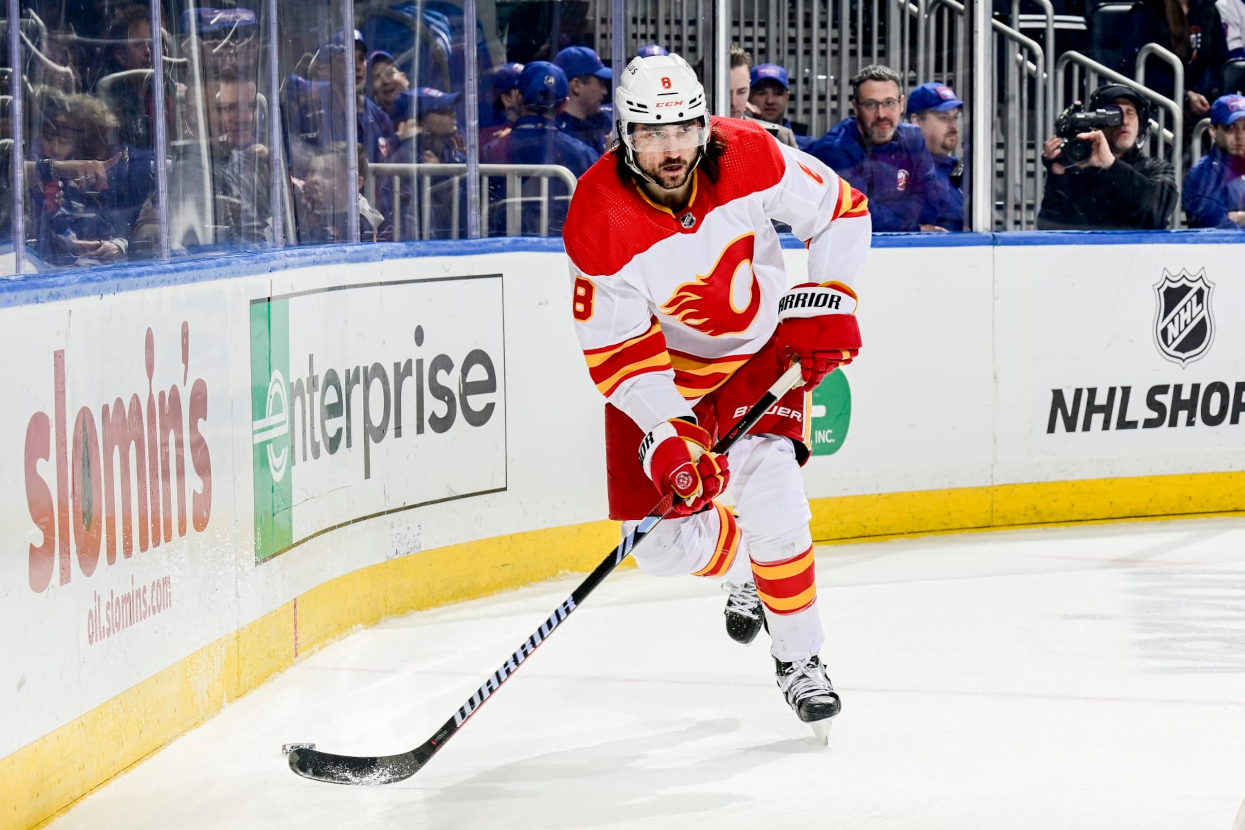 ELMONT, NEW YORK - FEBRUARY 10:  Chris Tanev #8 of the Calgary Flames carries the puck against the New York Islanders at UBS Arena on February 10, 2024 in Elmont, New York. (Photo by Steven Ryan/NHLI via Getty Images)