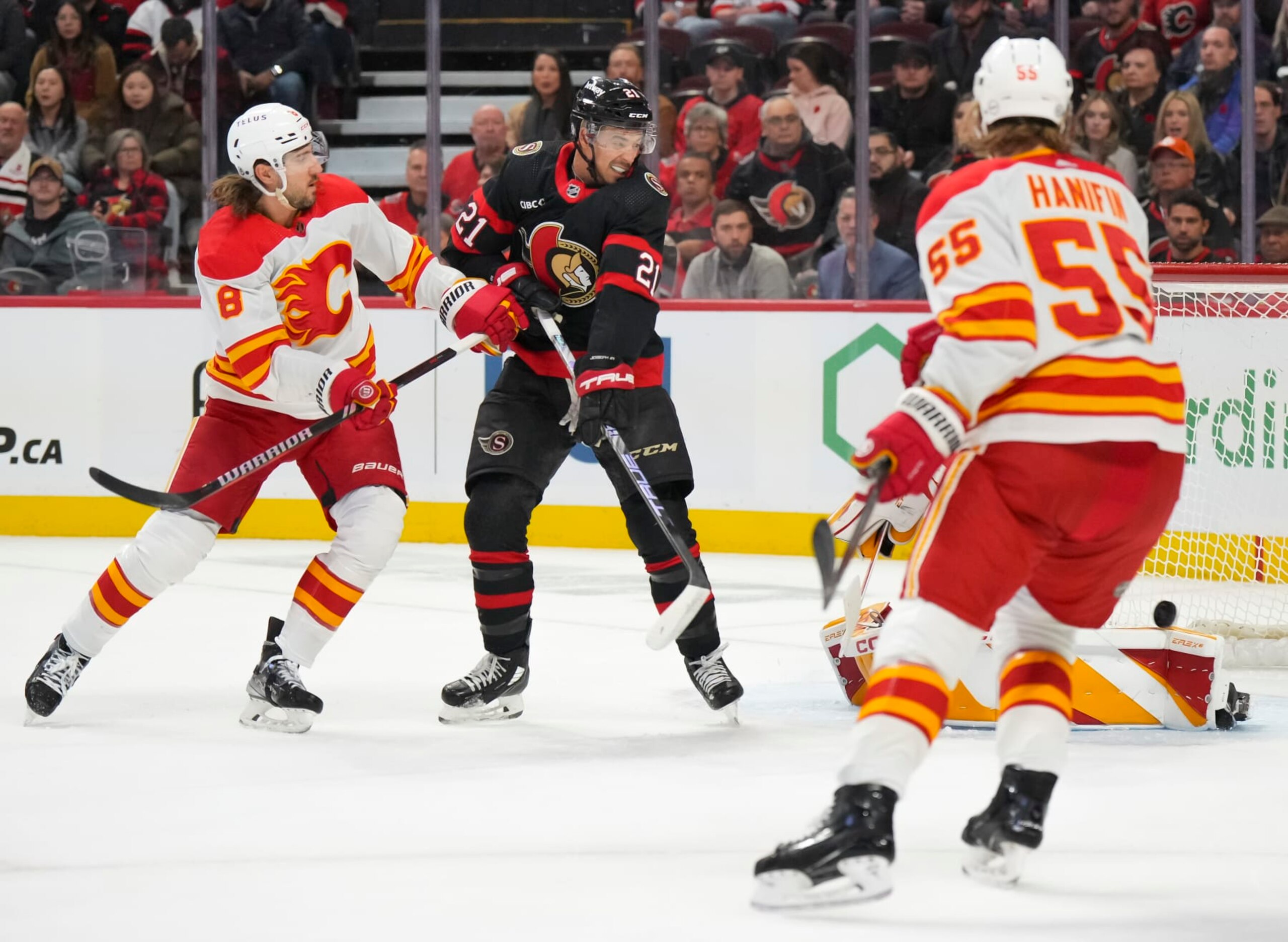 OTTAWA, CANADA - NOVEMBER 11: Mathieu Joseph #21 of the Ottawa Senators deflects the puck past Dustin Wolf #32 of the Calgary Flames as Chris Tanev #8 and Noah Hanifin #55 of the Calgary Flames defend during the first period at Canadian Tire Centre on November 11, 2023 in Ottawa, Ontario, Canada.  (Photo by André Ringuette/NHLI via Getty Images)