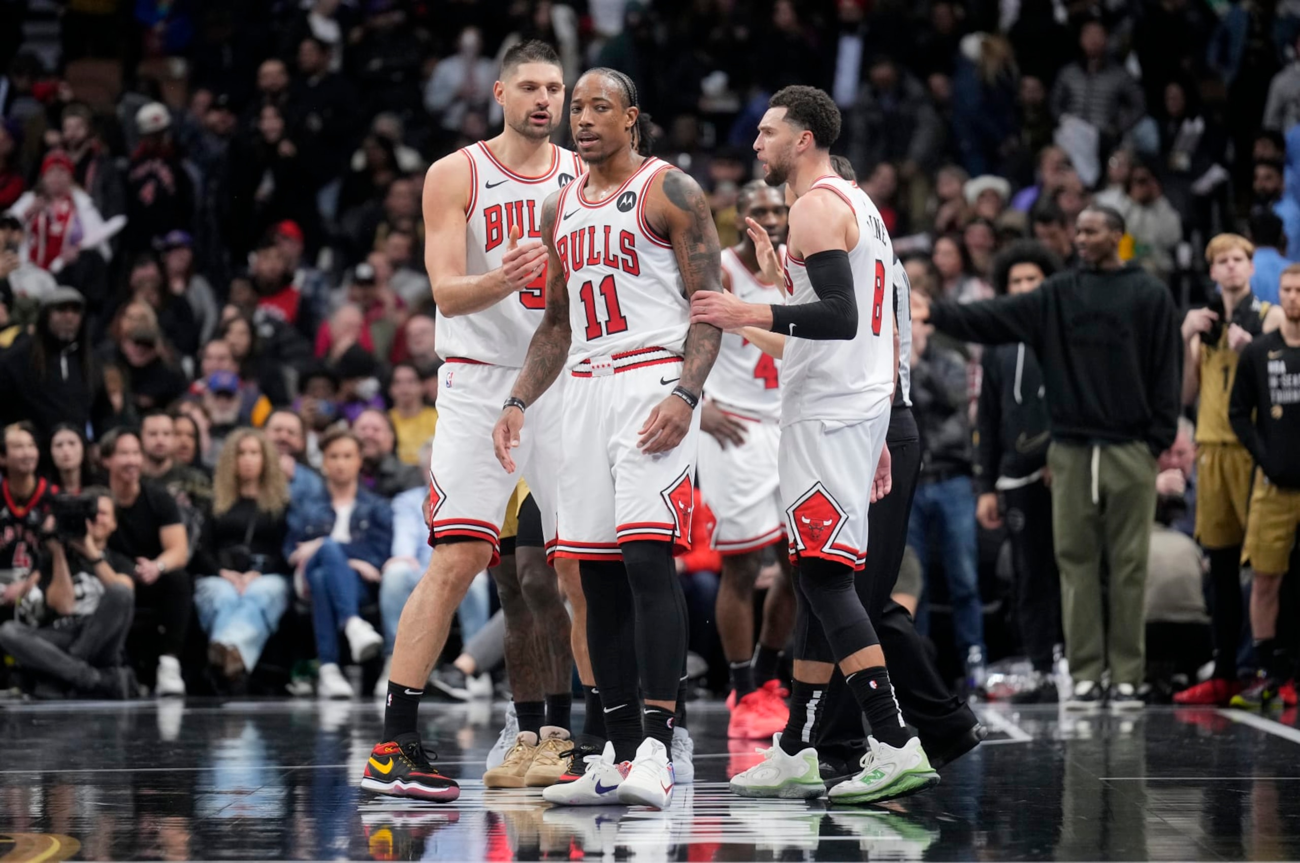 TORONTO, ON - NOVEMBER 24: DeMar DeRozan #11 of the Chicago Bulls reacts at the end of the second half with teammates Nikola Vucevic #9 (L) and Zach LaVine #8 (R) in the NBA In-Season Tournament game against the Toronto Raptors at the Scotiabank Arena on November 24, 2023 in Toronto, Ontario, Canada. NOTE TO USER: User expressly acknowledges and agrees that, by downloading and/or using this Photograph, user is consenting to the terms and conditions of the Getty Images License Agreement. (Photo by Mark Blinch/Getty Images)