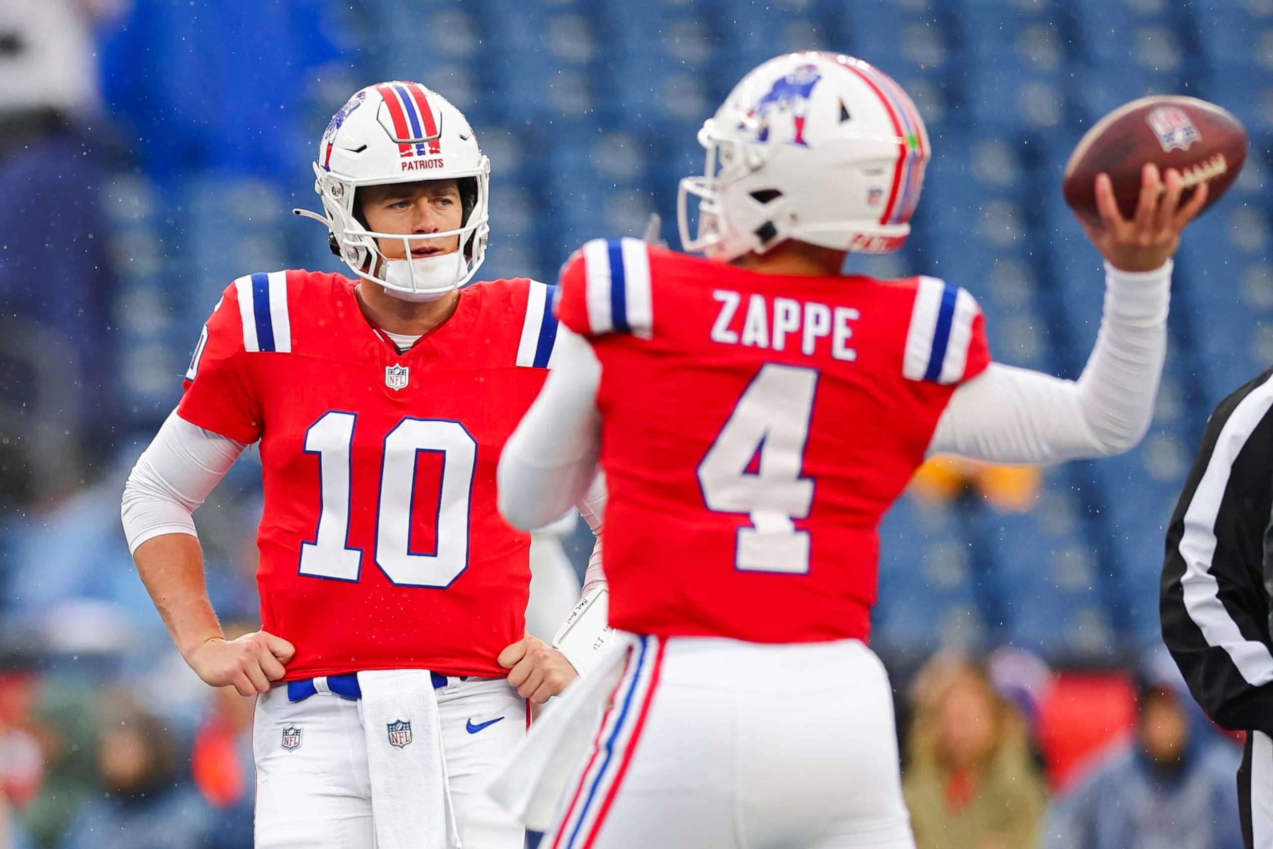 FOXBOROUGH, MASSACHUSETTS - DECEMBER 03: Bailey Zappe #4 of the New England Patriots warms up as Mac Jones #10 looks on before the game against the Los Angeles Chargers at Gillette Stadium on December 03, 2023 in Foxborough, Massachusetts. (Photo by Maddie Meyer/Getty Images)