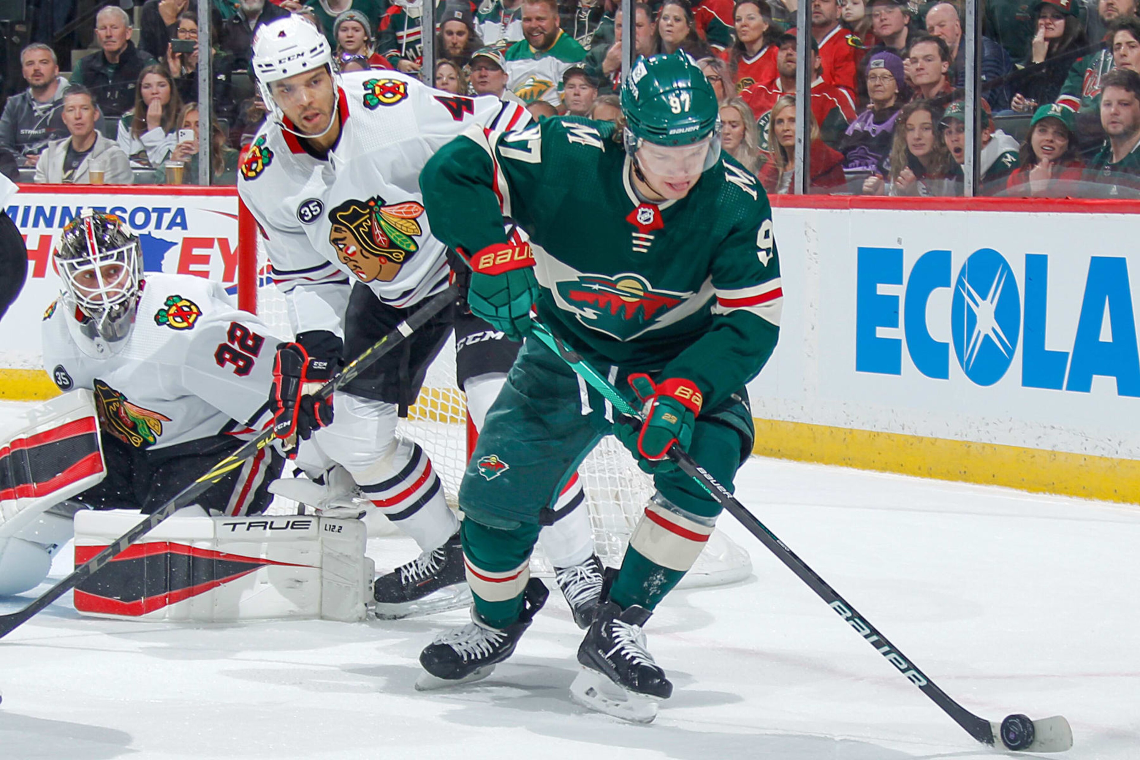 SAINT PAUL, MN - MARCH 19: Kirill Kaprizov #97 of the Minnesota Wild handles the puck with Seth Jones #4 and Kevin Lankinen #32 of the Chicago Blackhawks defending during the game at the Xcel Energy Center on March 19, 2022 in Saint Paul, Minnesota. (Photo by Bruce Kluckhohn/NHLI via Getty Images)
