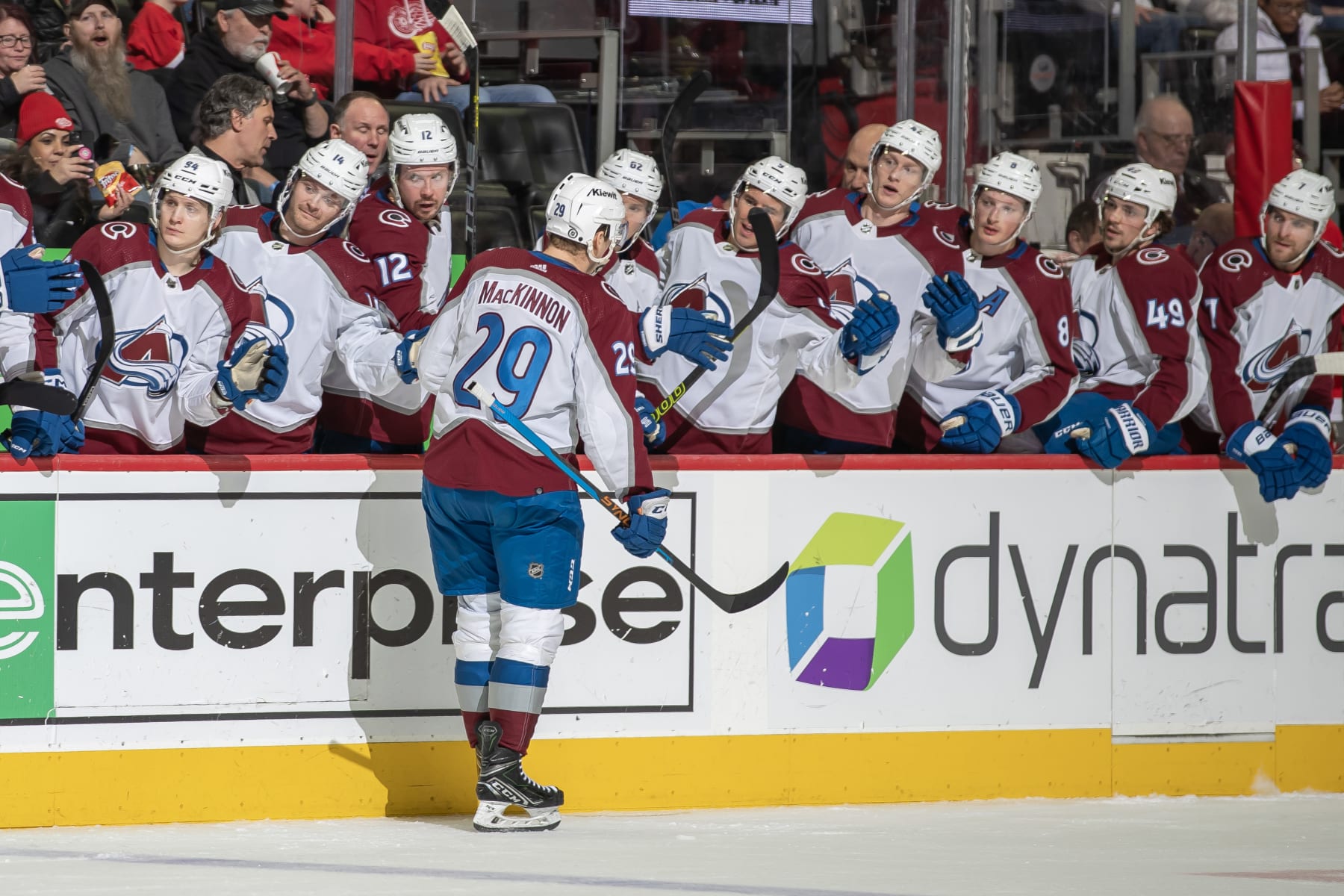 DETROIT, MI - FEBRUARY 22: Nathan MacKinnon #29 of the Colorado Avalanche pounds gloves with with teammates on the bench after his goal against the Detroit Red Wings during the second period at Little Caesars Arena on February 22, 2024 in Detroit, Michigan. (Photo by Dave Reginek/NHLI via Getty Images)