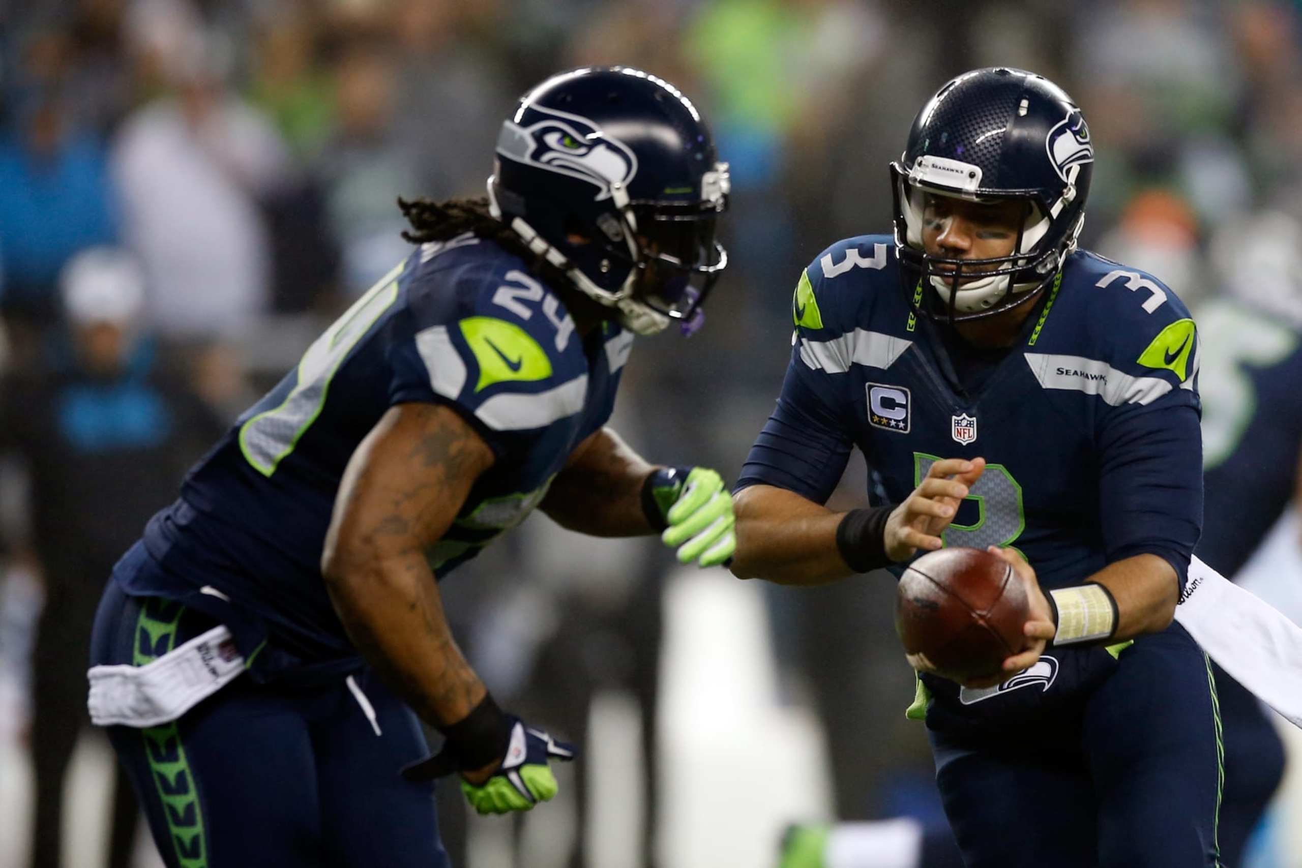 SEATTLE, WA - JANUARY 10:  Russell Wilson #3 of the Seattle Seahawks hands off the ball to Marshawn Lynch #24 in the first quarter against the Carolina Panthers during the 2015 NFC Divisional Playoff game at CenturyLink Field on January 10, 2015 in Seattle, Washington.  (Photo by Otto Greule Jr/Getty Images)