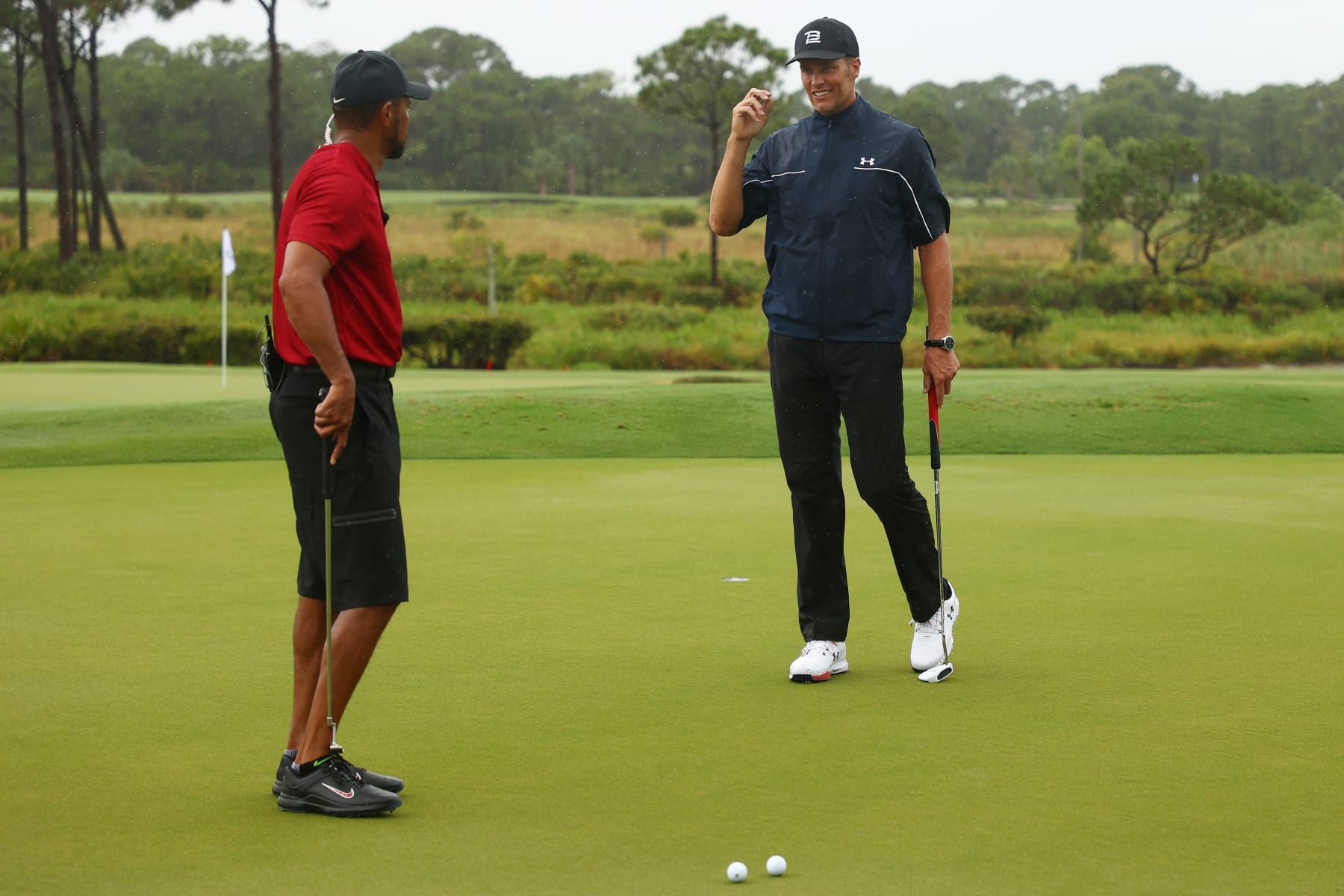 HOBE SOUND, FLORIDA - MAY 24: Tiger Woods and NFL player Tom Brady of the Tampa Bay Buccaneers warm up on the practice green during The Match: Champions For Charity at Medalist Golf Club on May 24, 2020 in Hobe Sound, Florida. (Photo by Mike Ehrmann/Getty Images for The Match)