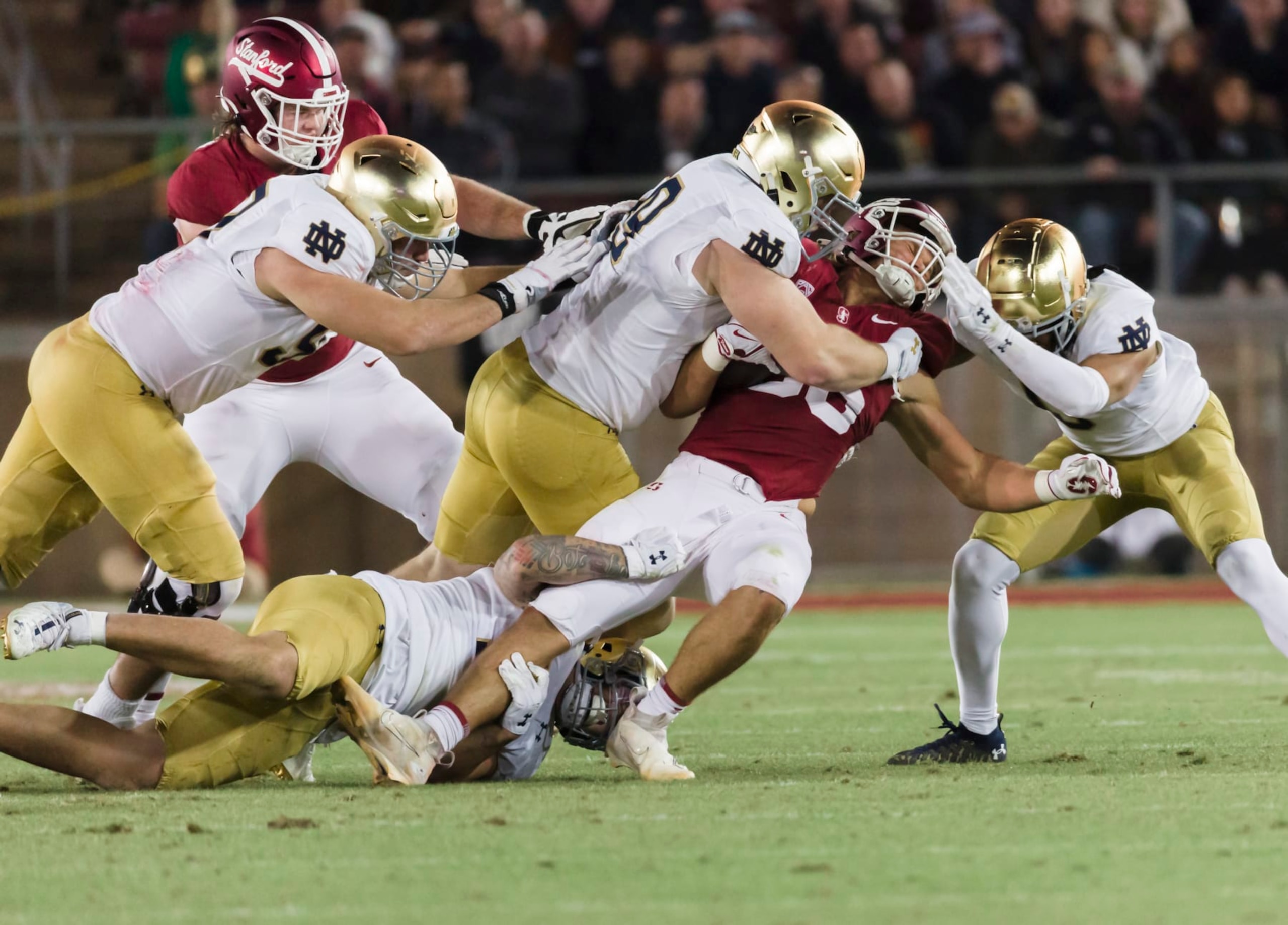 PALO ALTO, CA - NOVEMBER 25:  Sam Roush #86 of the Stanford Cardinal is tackled by Thomas Harper #13, Rylie Mills #99, Xavier Watts #0, and Gabriel Rubio #97 of the Notre Dame Fighting Irish during a college football game on November 25, 2023 at Stanford Stadium in Palo Alto, California.  (Photo by David Madison/Getty Images)
