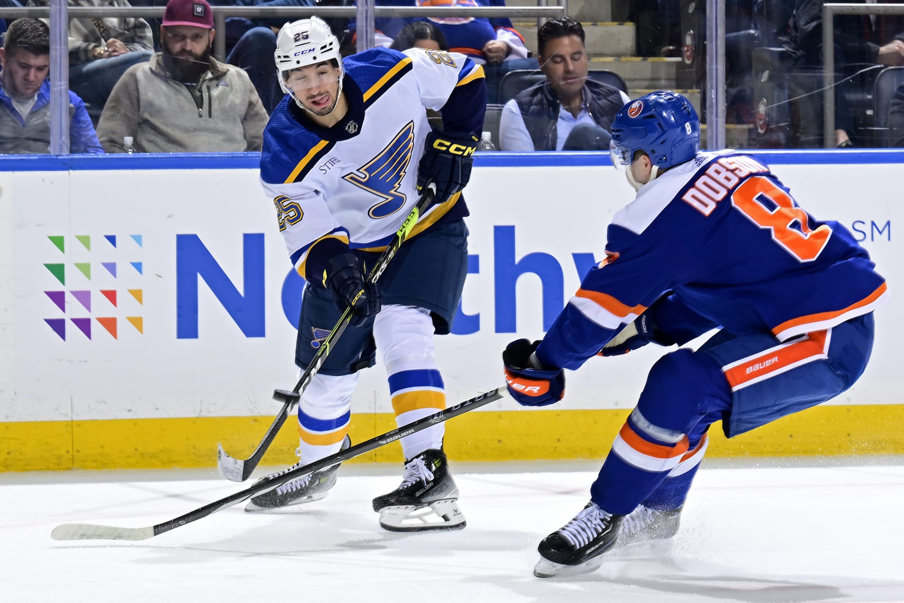 ELMONT, NEW YORK - MARCH 05:  Jordan Kyrou #25 of the St. Louis Blues is defended by Noah Dobson #8 of the New York Islanders during the second period at UBS Arena on March 05, 2024 in Elmont, New York. (Photo by Steven Ryan/NHLI via Getty Images)