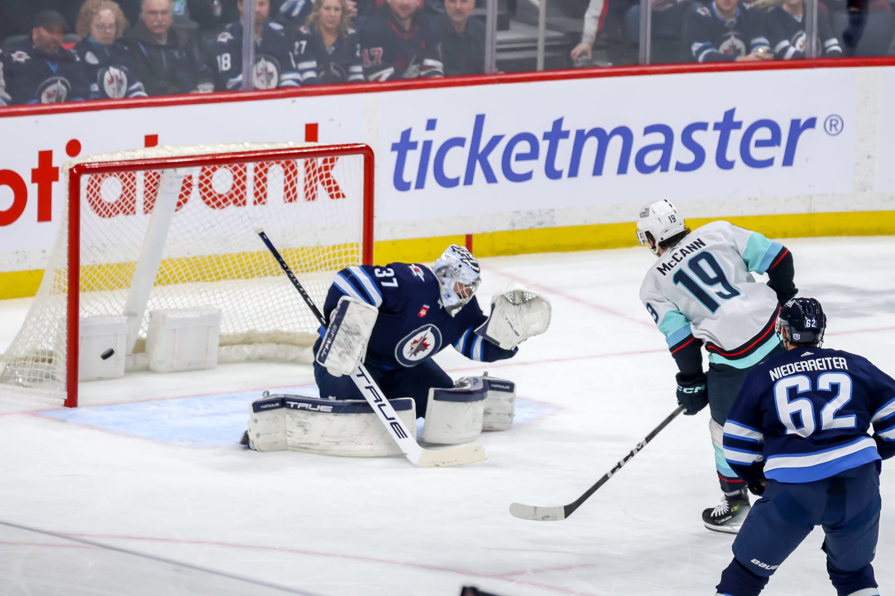 WINNIPEG, CANADA - MARCH 5: Jared McCann #19 of the Seattle Kraken shoots the puck past goaltender Connor Hellebuyck #37 of the Winnipeg Jets for a second period short-handed goal at the Canada Life Centre on March 5, 2024 in Winnipeg, Manitoba, Canada. (Photo by Jonathan Kozub/NHLI via Getty Images)